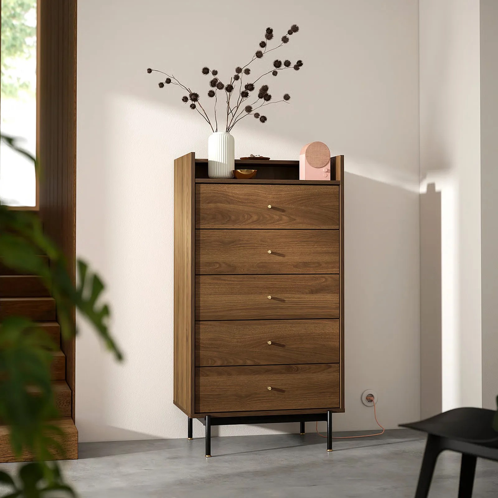 The IKEA RADMANSO five drawer dresser shown against a white wall with a flower vase and other knick knacks displayed on the top
