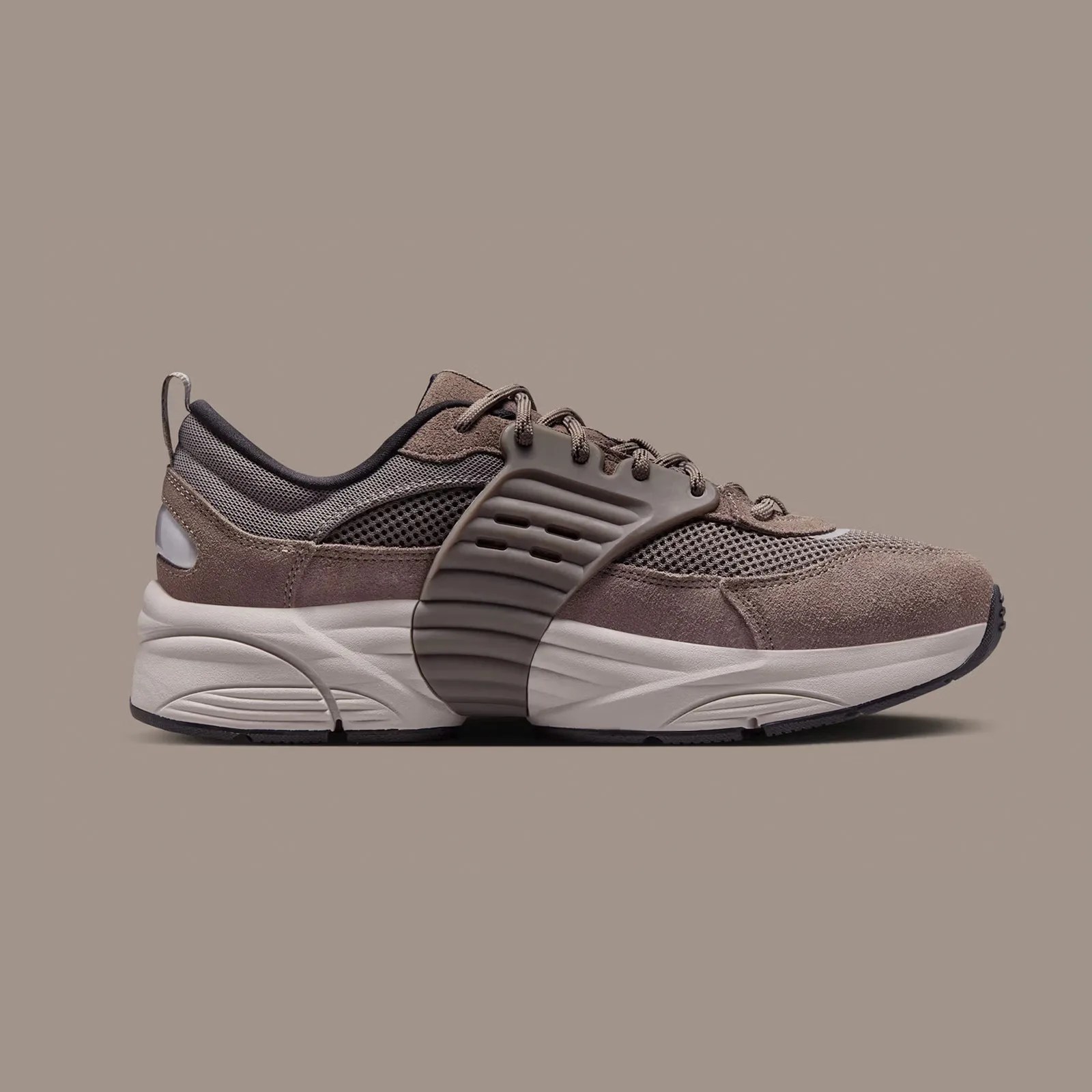 A single Jordan Trunner O/S sneaker shown in profile with the toe pointing to the right of the image frame in the "Cave Stone" dark brown color against a taupe background.