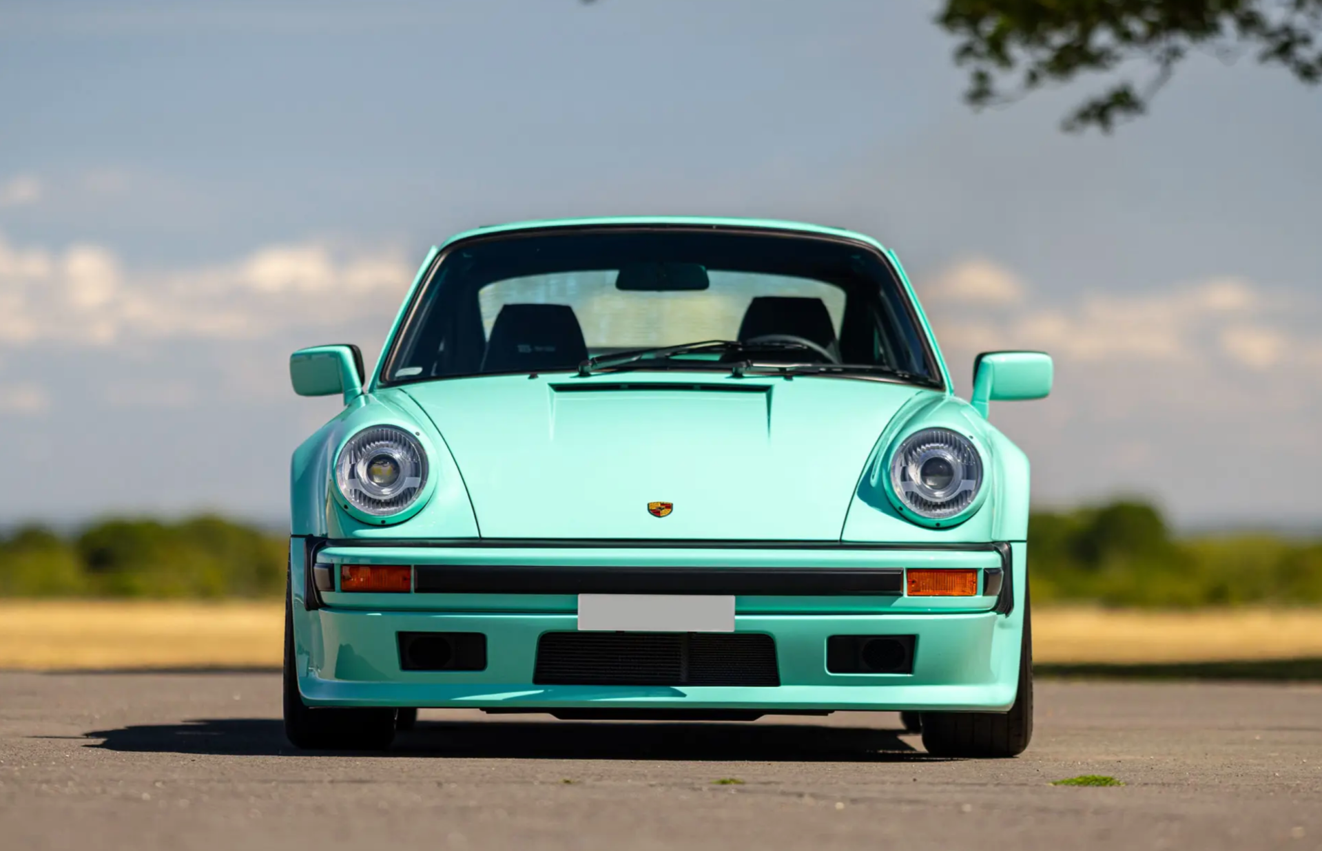 a front-on photo of a classic mint green porsche 911