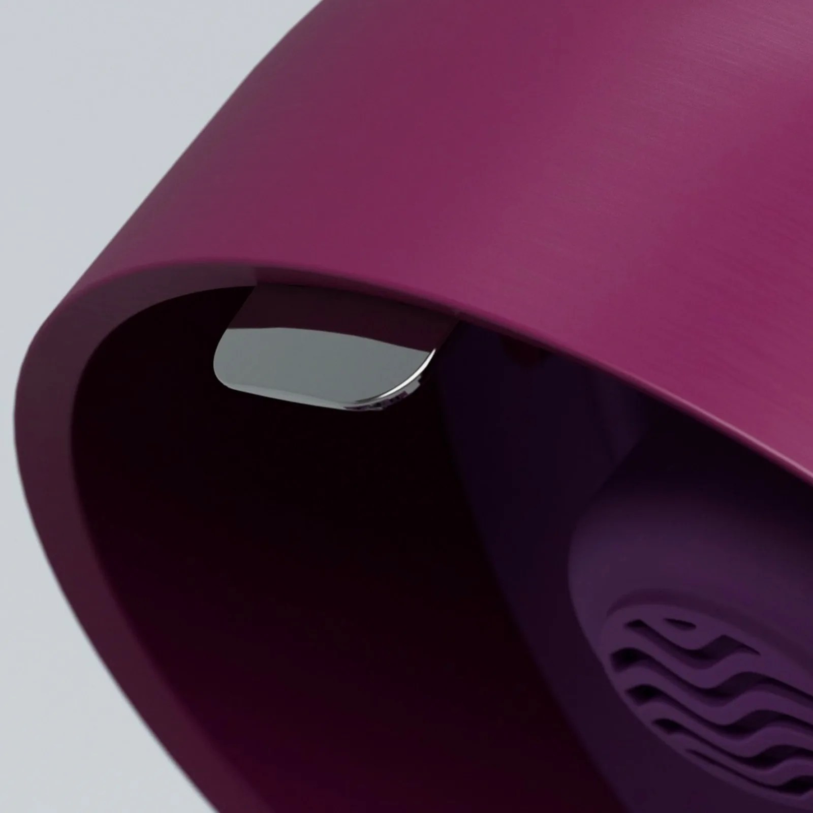 Close-up of a purple cylindrical object with a smooth, matte finish, featuring a small, shiny metallic tab or lever on the inner edge. The interior shows a vent-like pattern in a darker purple shade.