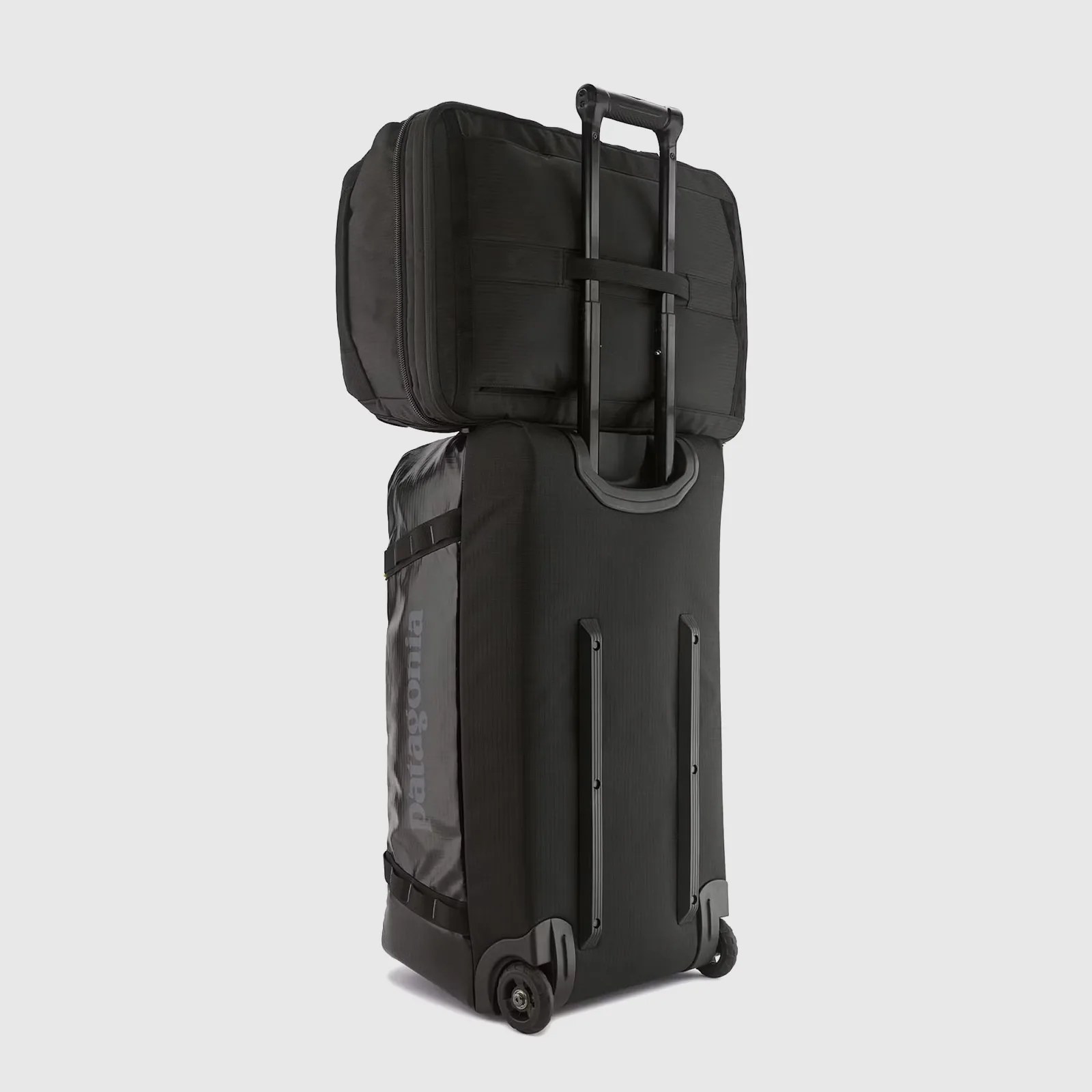 The Patagonia Black Hole MLC 45L backpack in black is shown sitting on top of a roller board.