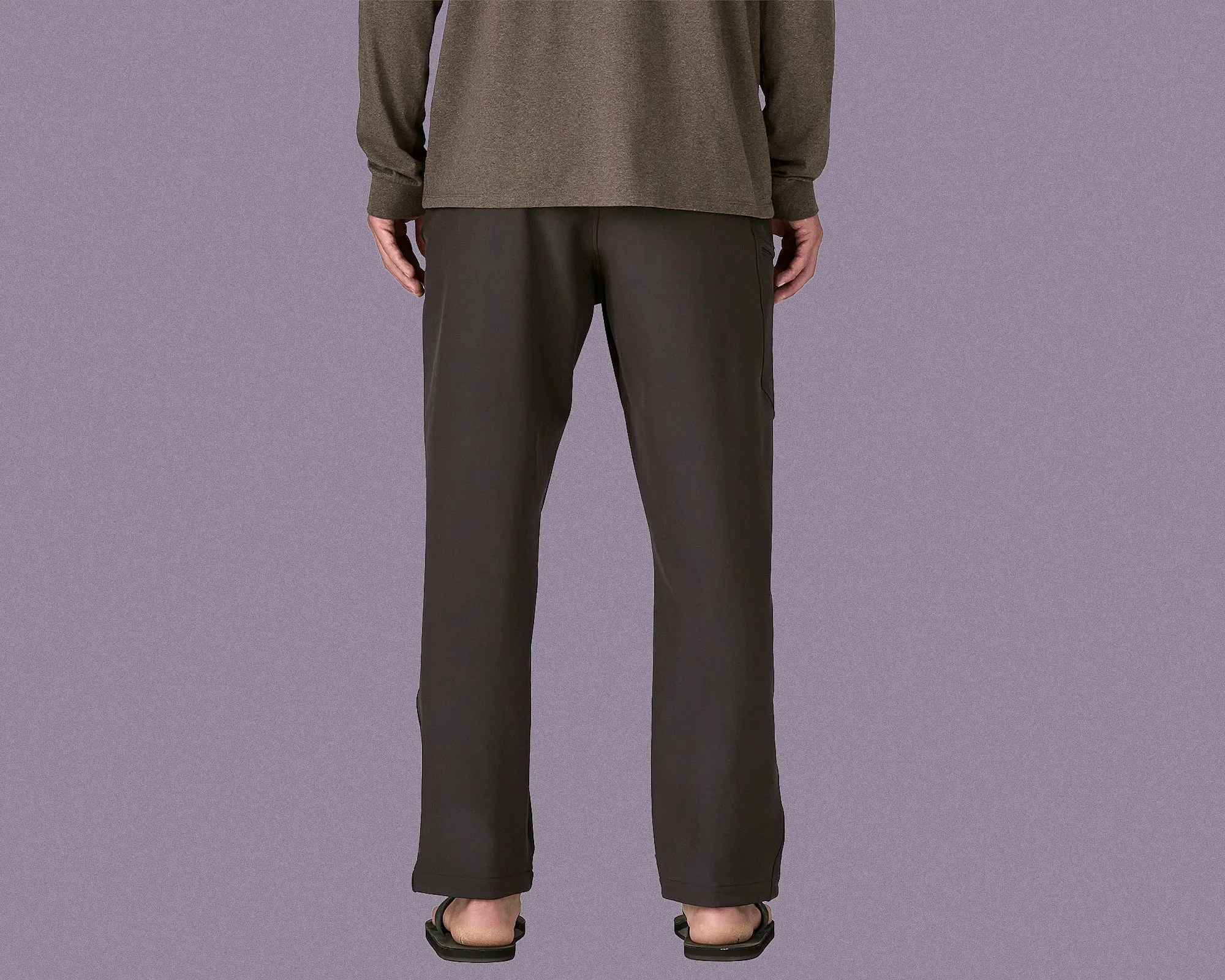 Dark brown straight-leg pants with a relaxed fit, shown from the back. The pants have a side pocket on the right leg and are paired with black sandals. The person wearing them is also wearing a long-sleeve brown top.