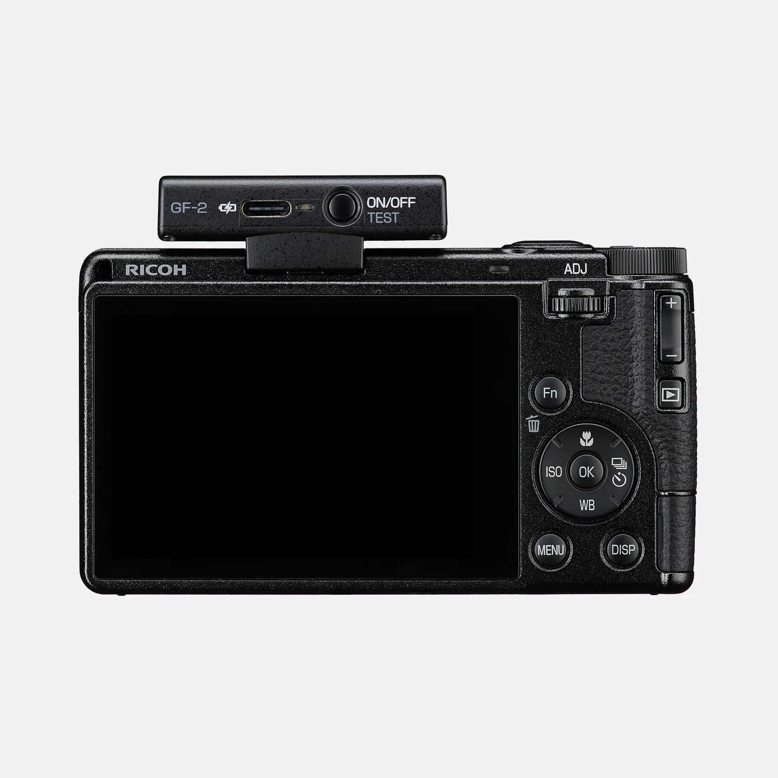 Back view of a black Ricoh digital camera with a large LCD screen, multiple control buttons including Fn, ISO, WB, OK, MENU, DISP, and a directional pad. On top of the camera, there is a small black accessory labeled "GF-2" with an ON/OFF TEST button and a USB-C port.