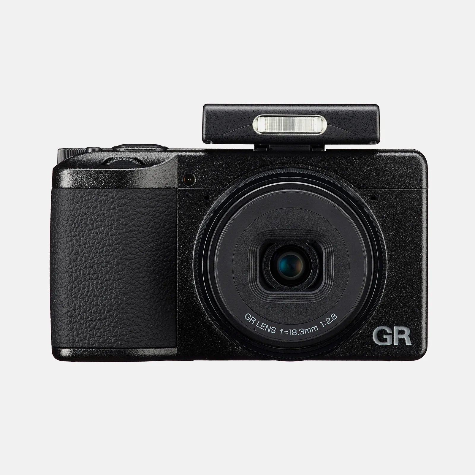 Compact black digital camera with a textured grip on the left side, a large central lens labeled "GR LENS f=18.3mm 1:2.8," and a pop-up flash unit extended on top. The camera body has a matte finish with the letters "GR" printed in silver on the bottom right corner.