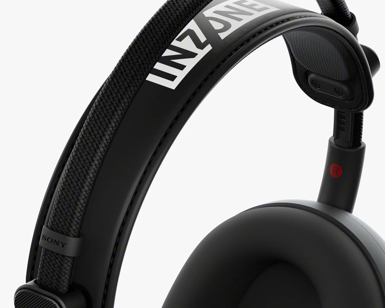 Close-up of the right side of a black Sony INZONE gaming headset, showing the padded headband with the INZONE logo and the cushioned ear cup marked with a red "R" for the right side. The headband features a textured fabric strap and a smooth leather-like padding underneath.