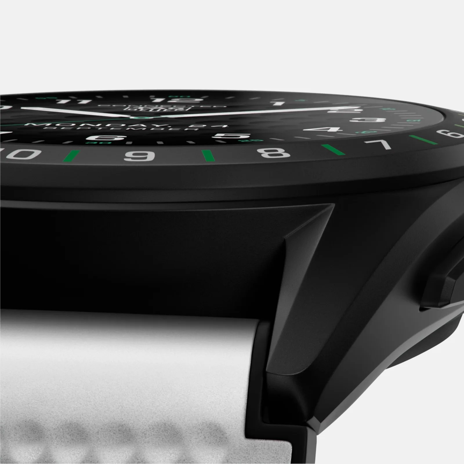 Close-up side view of a black wristwatch with a black dial featuring white and green numerals and markings, a white watch strap, and a visible crown on the right side. The watch face shows the day and date.