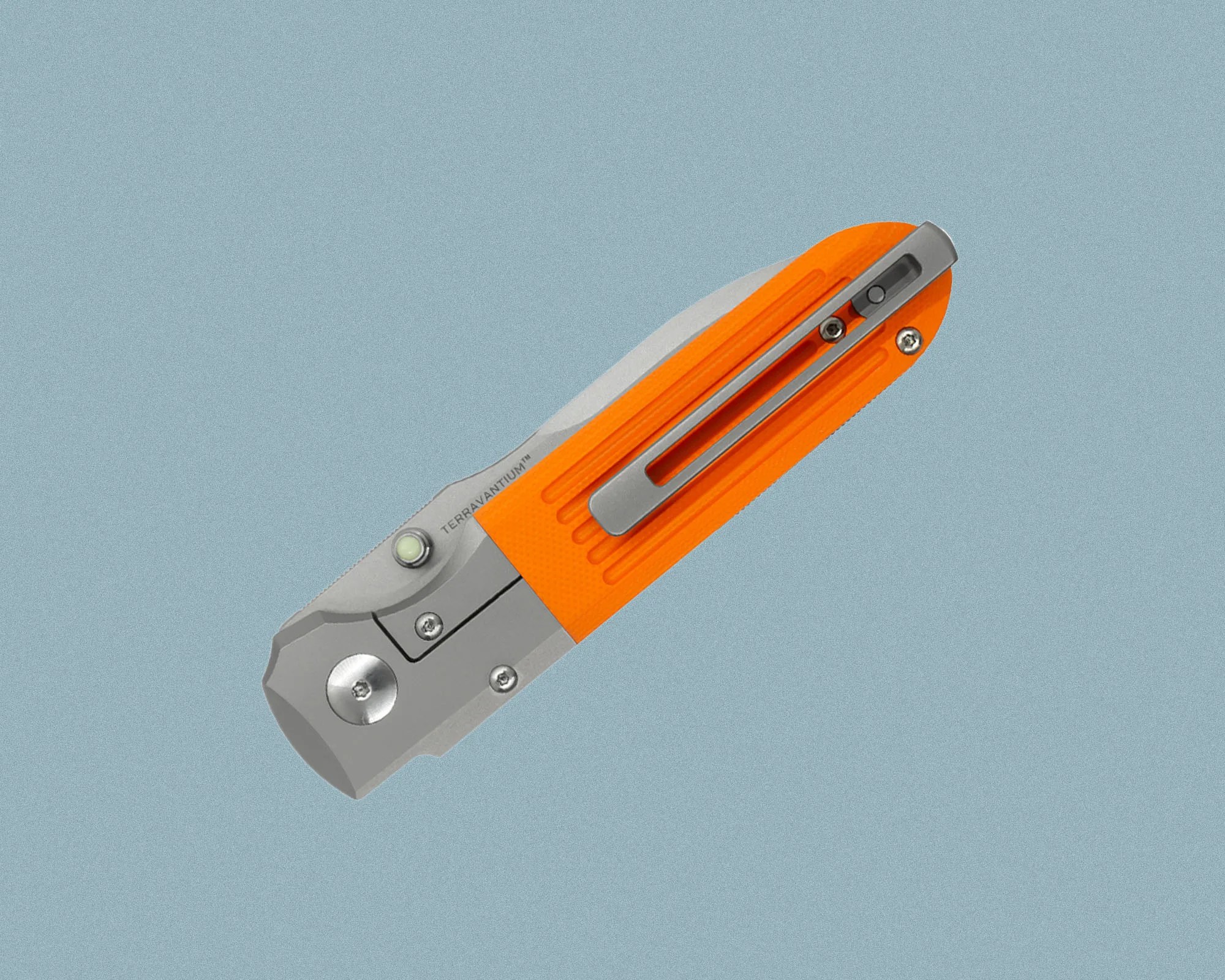 Folding pocket knife with a bright orange handle and a silver metal clip. The blade is partially visible, and the knife features a thumb stud for easy opening. The handle has textured grooves for grip, and the brand name "TERRAVANTIUM" is etched near the blade pivot.