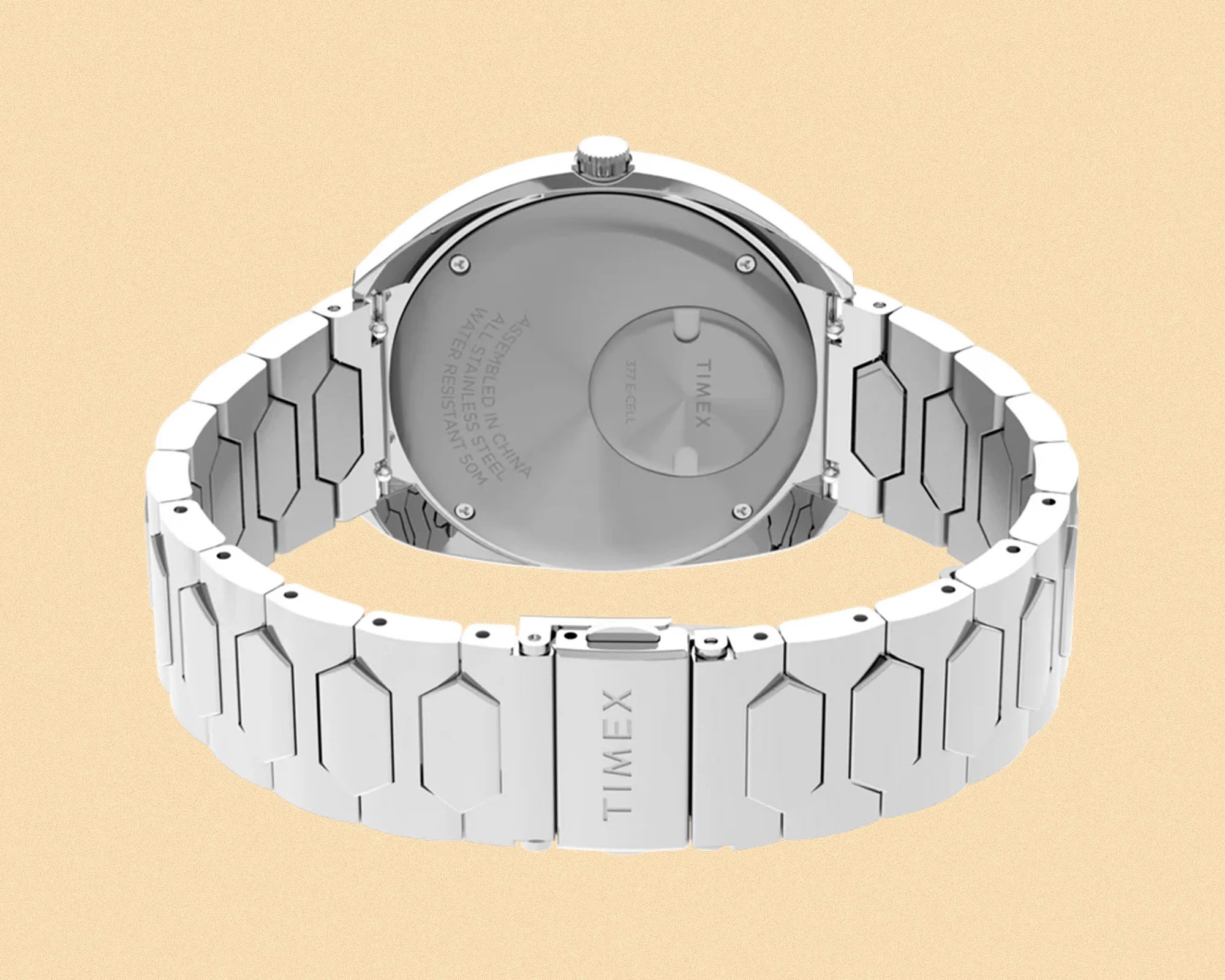 Silver stainless steel Timex wristwatch with a hexagonal link bracelet, shown from the back. The watch case back is engraved with details including "Assembled in China," "All Stainless Steel," "Water Resistant 50M," and "Timex" with a battery compartment labeled "377 E-Cell." The clasp is also engraved with "TIMEX.