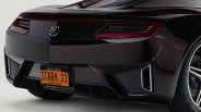 Rear view of a dark-colored Acura sports car featuring sleek taillights, a New York license plate with the text "STARK 33," and a sporty rear diffuser with integrated exhaust outlets. The car has a polished finish and visible Hankook tires.