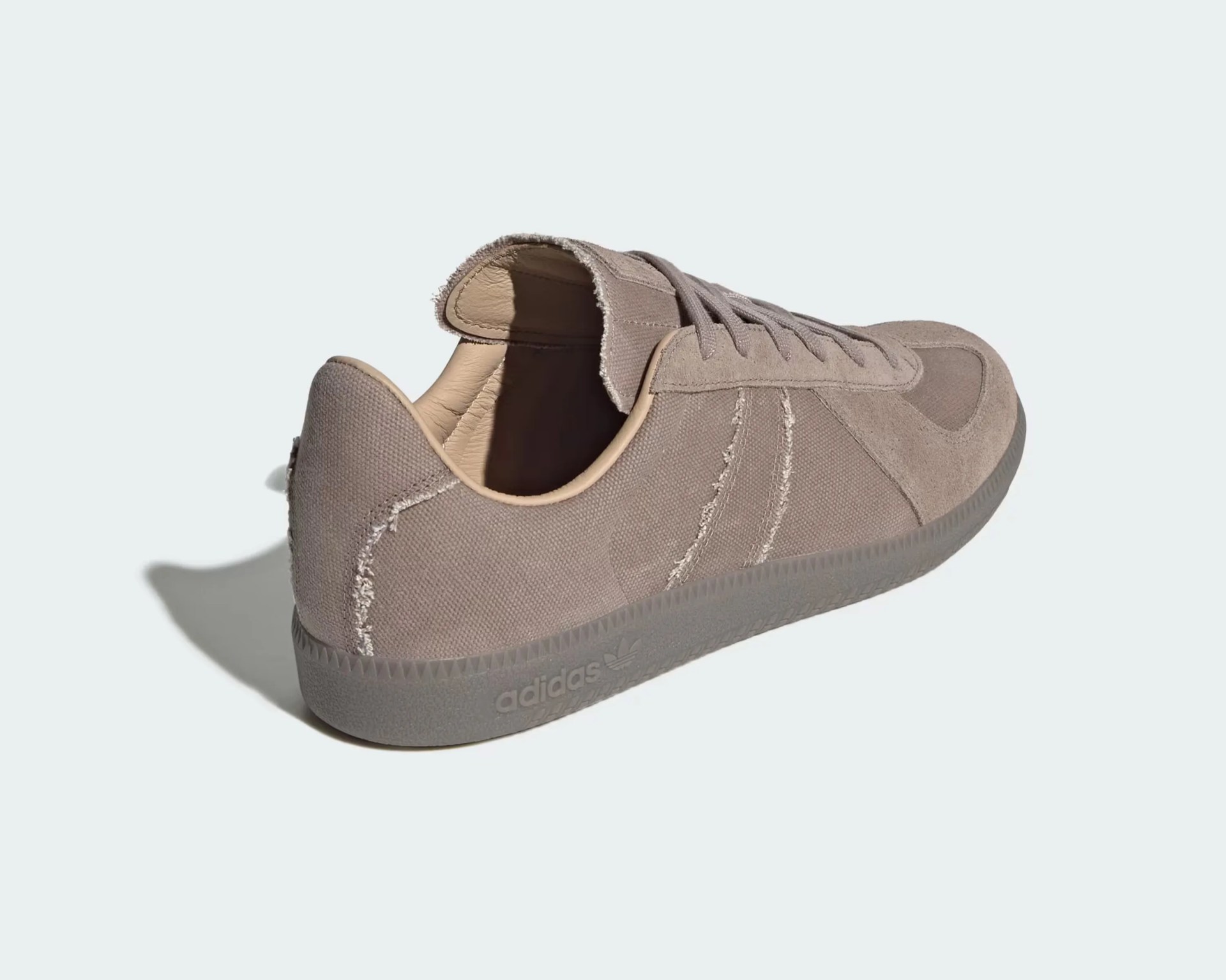 Light brown Adidas sneaker with a suede and canvas upper, featuring a textured rubber sole and visible stitching details. The shoe has a low profile with laces and a slightly frayed tongue edge. The Adidas logo is embossed on the side of the sole.