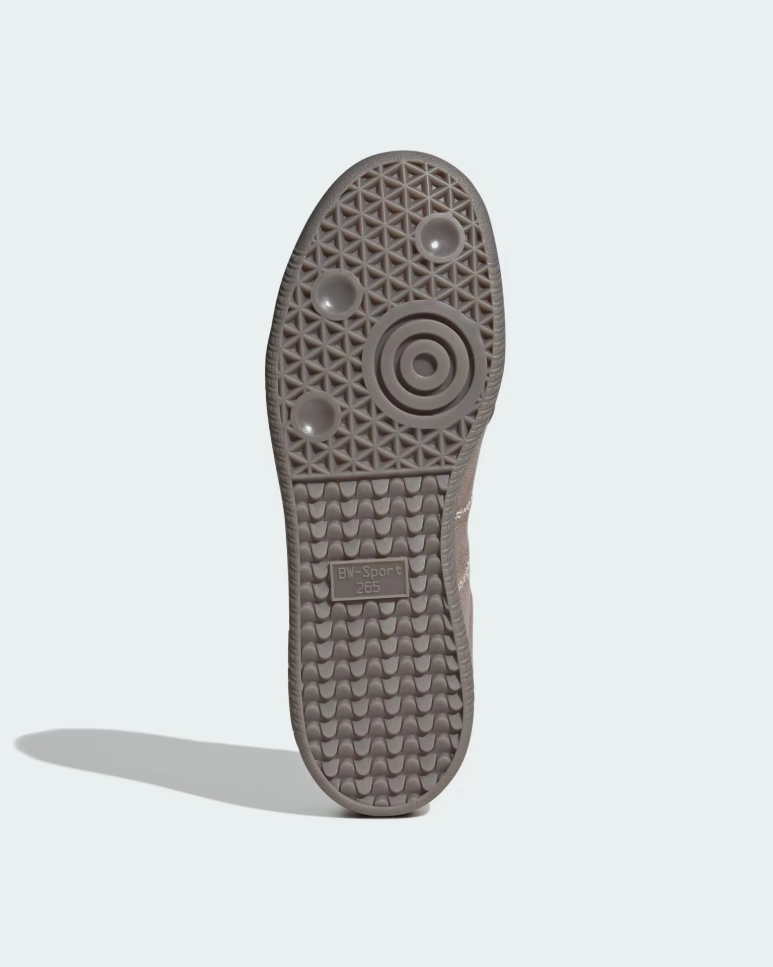 Sole of a shoe with a textured pattern featuring triangular shapes at the top, circular indentations, and concentric circles near the ball of the foot. The bottom half has a wavy tread pattern with a rectangular label reading "BW-Sport 265." The sole is a muted grayish-brown color.