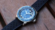 Blancpain Fifty Fathoms dive watch with a black dial, luminous hour markers, and a black textured rubber strap, placed on a wooden surface. The watch features a rotating bezel with minute markings and a stainless steel case.