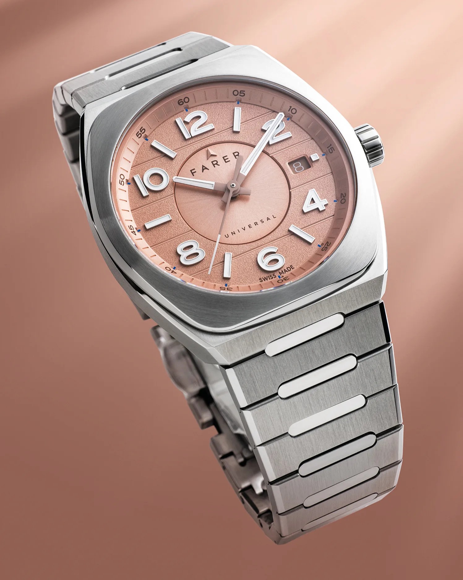 Stainless steel wristwatch with a brushed metal finish and a salmon-colored textured dial. The dial features large white Arabic numerals, silver hour and minute hands, a thin second hand, and a date window at the 3 o'clock position. The watch face is marked with "FARER," "UNIVERSAL," and "SWISS MADE." The bracelet has a distinctive link design with polished rectangular accents.