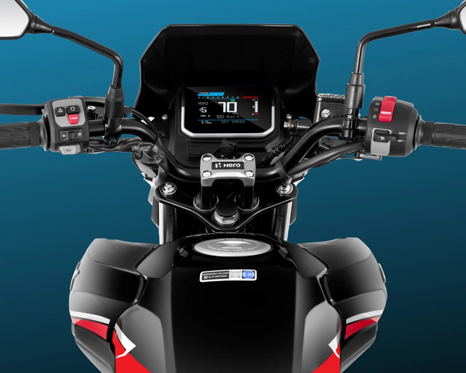 Motorcycle dashboard and handlebars with a digital display showing speed and other information, black fuel tank with red and white accents, and rearview mirrors on both sides. The brand "Hero" is visible on the handlebar clamp.