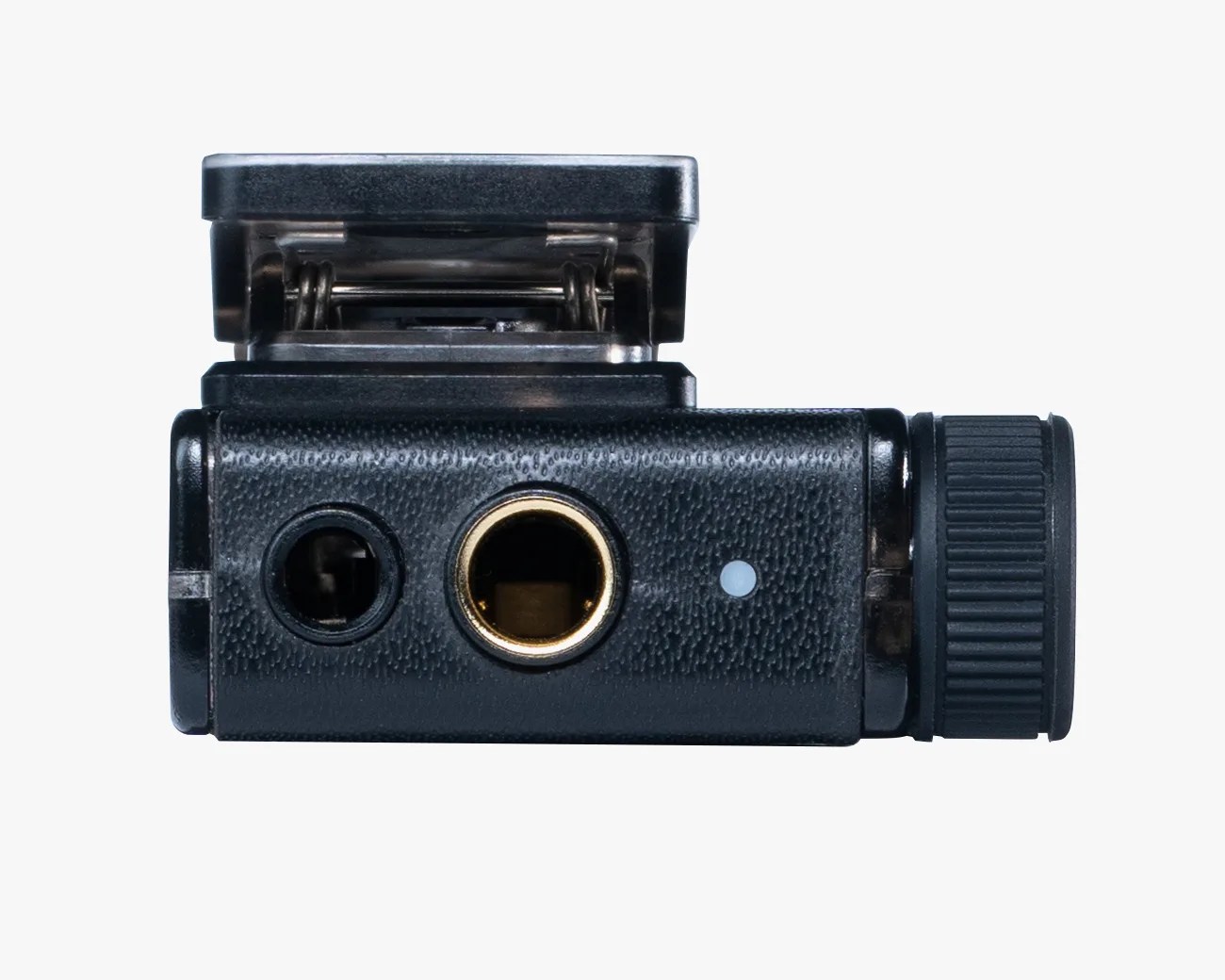 Black camera hot shoe adapter with a textured surface, featuring a metal spring-loaded clip on top, a 3.5mm jack port, a 1/4-inch threaded hole, and a ridged adjustment knob on the side.