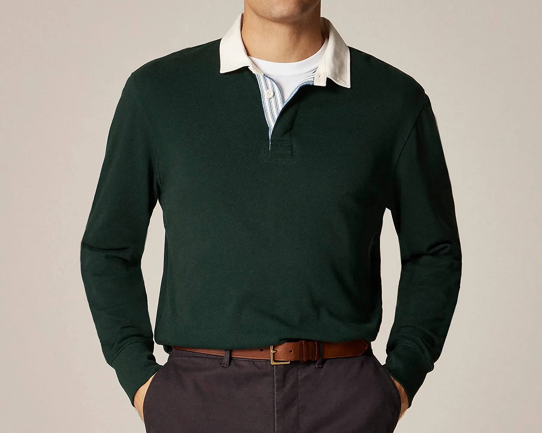 Dark green long-sleeve rugby shirt with a white collar and a partially visible blue and white striped placket, worn tucked into dark pants with a brown leather belt.