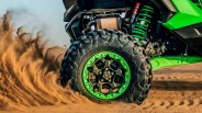 a photo of a kawasaki UTV wheel kicking up sand