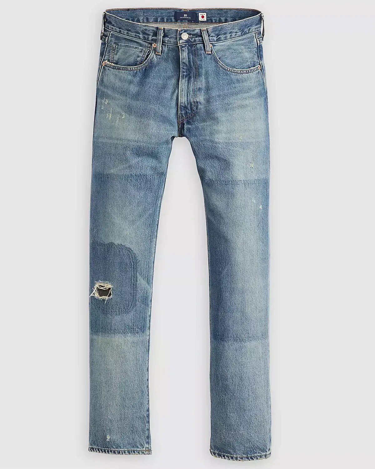 Light blue denim jeans with a slim fit design, featuring a distressed patch with a small hole on the left knee area. The jeans have a classic five-pocket style with visible stitching and a button closure at the waist. The fabric shows subtle fading and whiskering for a worn-in look.