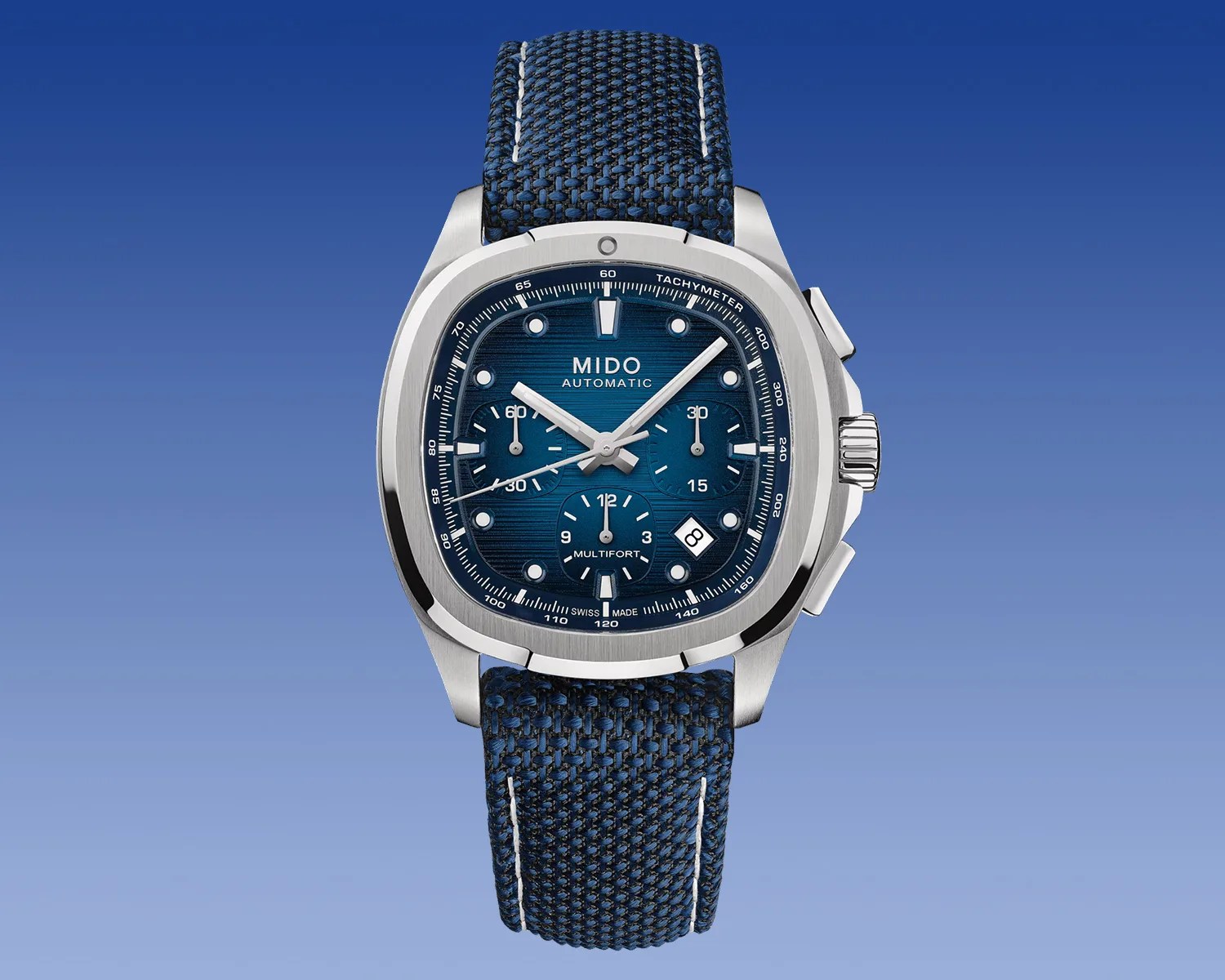 Blue Mido Multifort automatic wristwatch with a square stainless steel case, blue textured dial featuring three subdials, white hour markers, and a date window at 4 o'clock, paired with a blue woven fabric strap with white stitching.