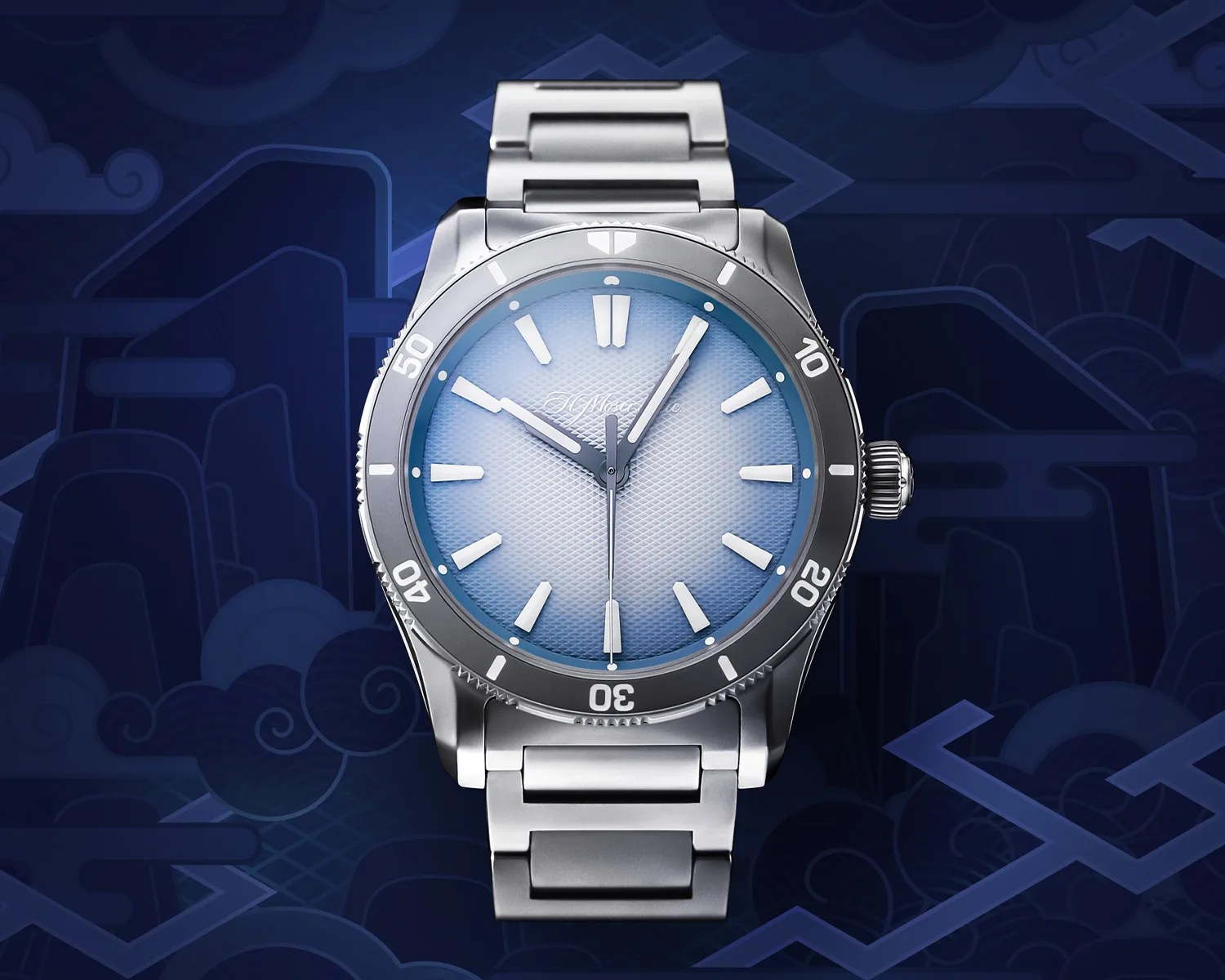 A silver moser wristwatch with a gradient blue dial that fades from light blue in the center to a darker blue near the edges. The watch has a textured pattern on the dial, thick white hour markers, and three hands: an hour hand, a minute hand, and a thin second hand. The bezel is silver with white numerals and markers at intervals of ten. The watch band is a matching silver metal link bracelet. The background is a dark blue with abstract cloud and geometric patterns.