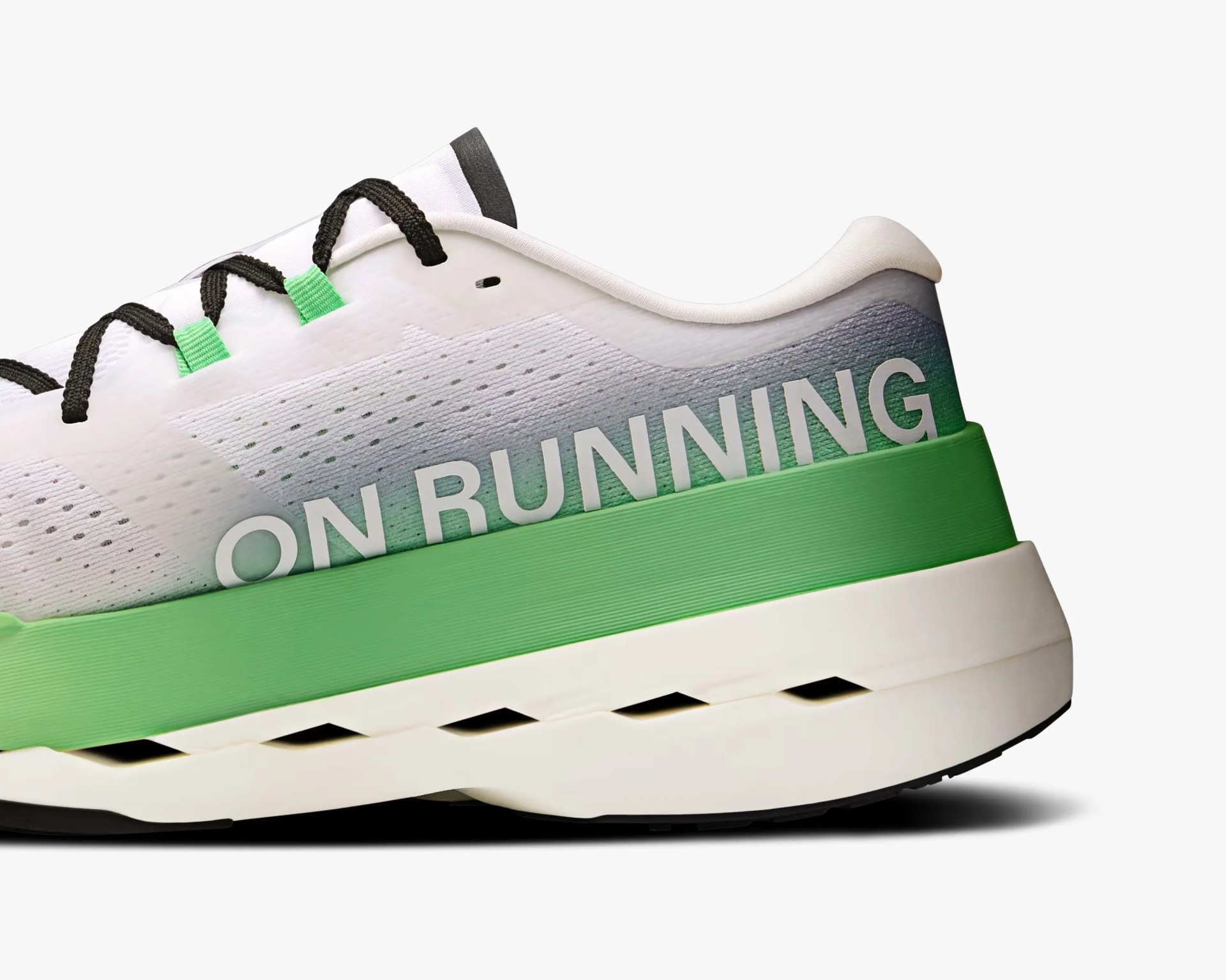 Close-up of the heel and midsection of a white running shoe with black laces and green lace loops. The shoe features a green midsole and a white outsole with black accents. The side of the shoe displays the text "ON RUNNING" in large white letters. The upper material has a subtle gradient from white to a darker shade near the heel.