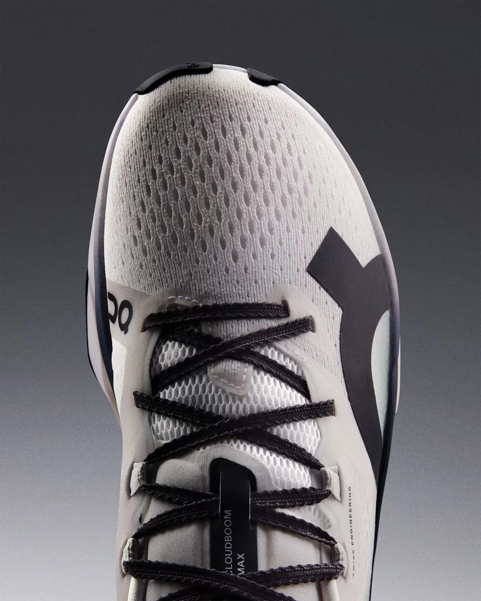 White athletic shoe with black laces and a black logo on the side, featuring a breathable mesh upper and a tag labeled "CLOUDBOOM MAX" on the tongue.