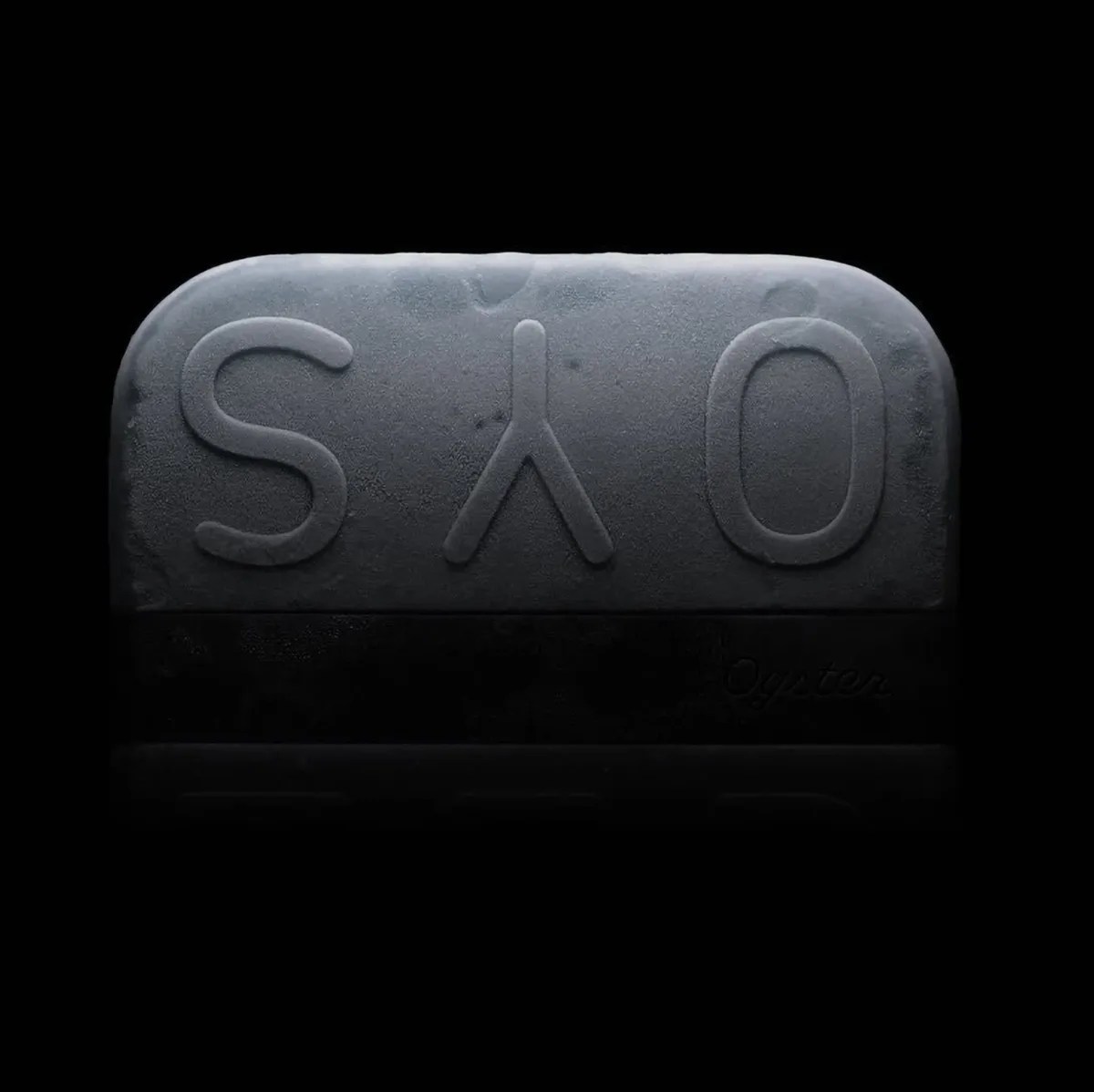 A close-up of a frosted, dark gray keycap with the characters "S", a lambda symbol (λ), and "O" embossed on it, set against a black background. The keycap has a slightly rounded top edge and a textured surface.