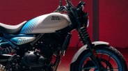 Close-up of a Royal Enfield motorcycle, specifically the Guerilla 350 model, featuring a white fuel tank with blue stripes, a black engine, and a front wheel with a white fender and blue rim. The background is a solid dark red.