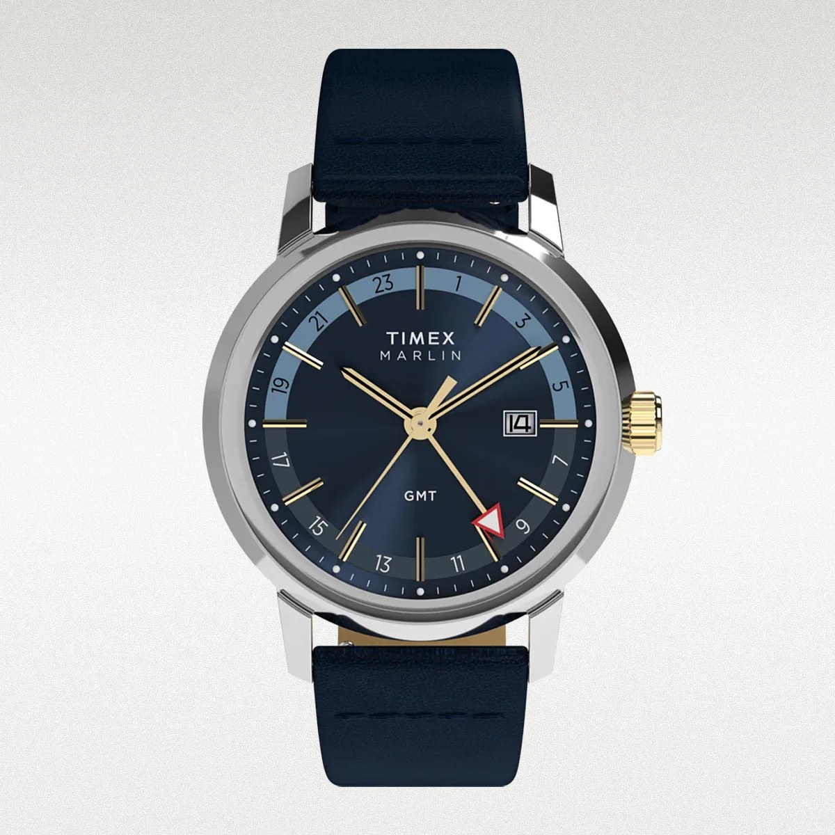 Timex Marlin GMT watch with a round silver case, dark blue dial, and gold-tone hour markers and hands. It features a date window at 3 o'clock, a 24-hour GMT scale on the inner ring, and a navy blue leather strap. The crown is gold-tone.