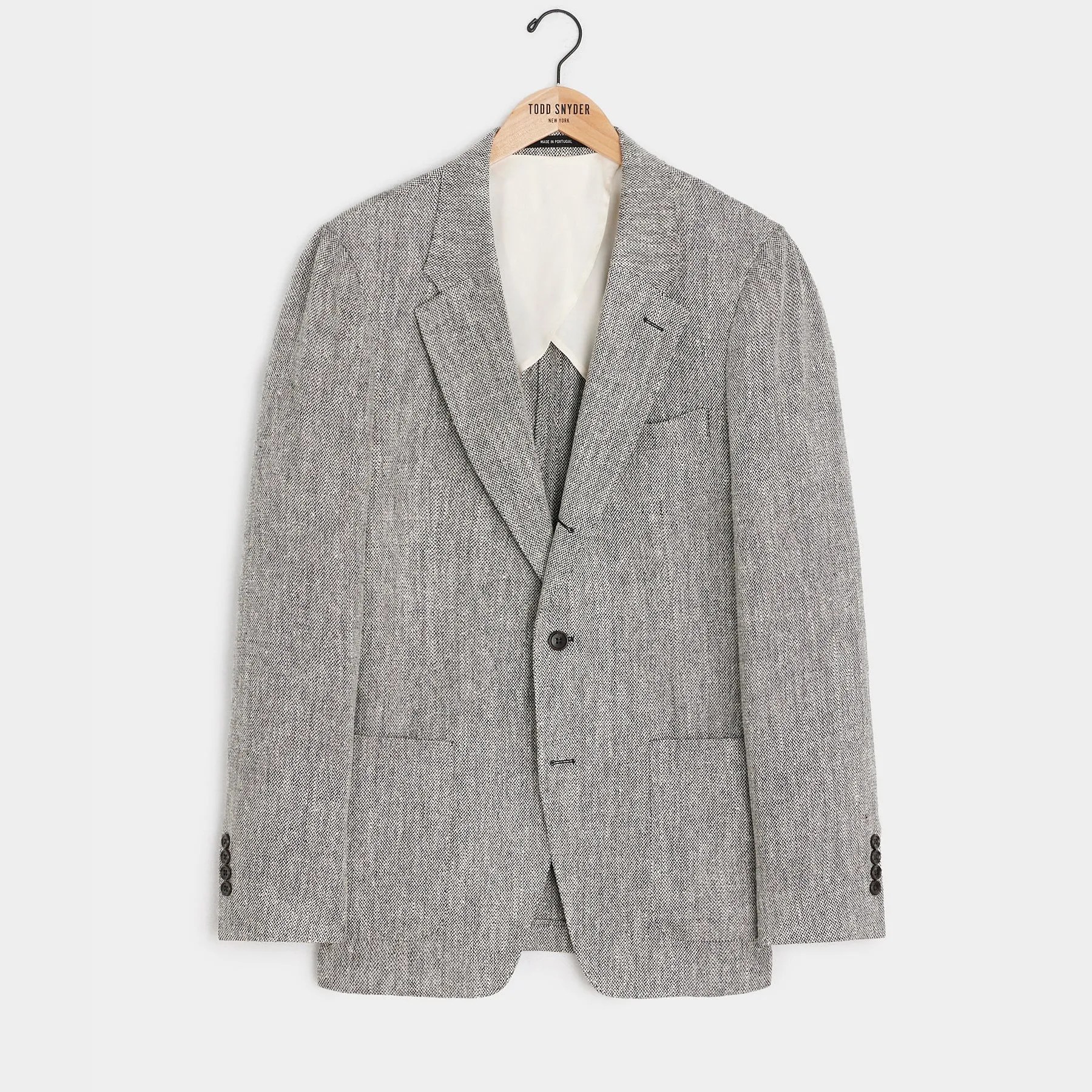Gray textured blazer with a notched lapel, two front flap pockets, a chest pocket, and dark buttons on the front and cuffs, hanging on a wooden hanger.