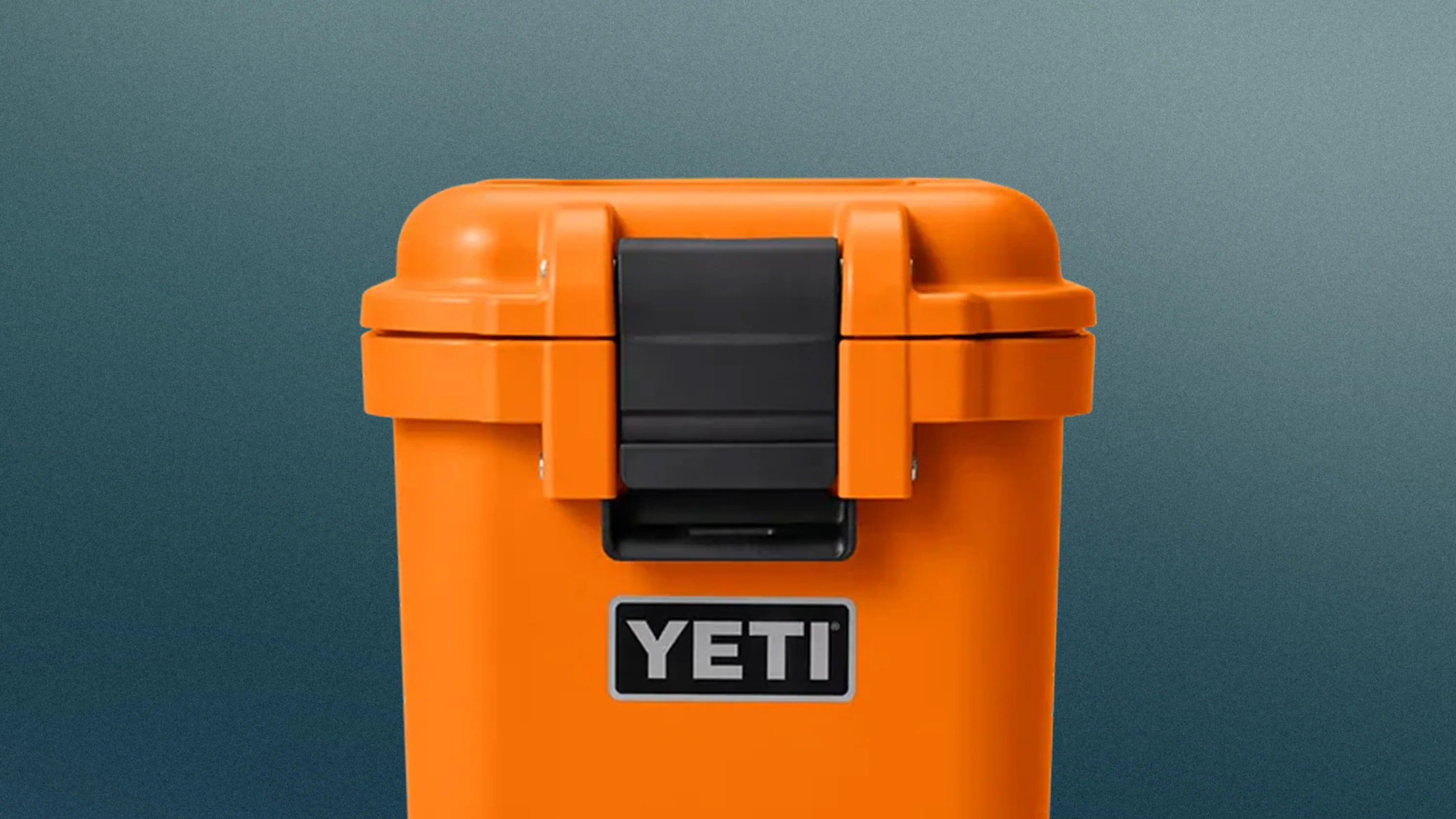 Orange YETI cooler with a black latch on the front against a gradient blue background.