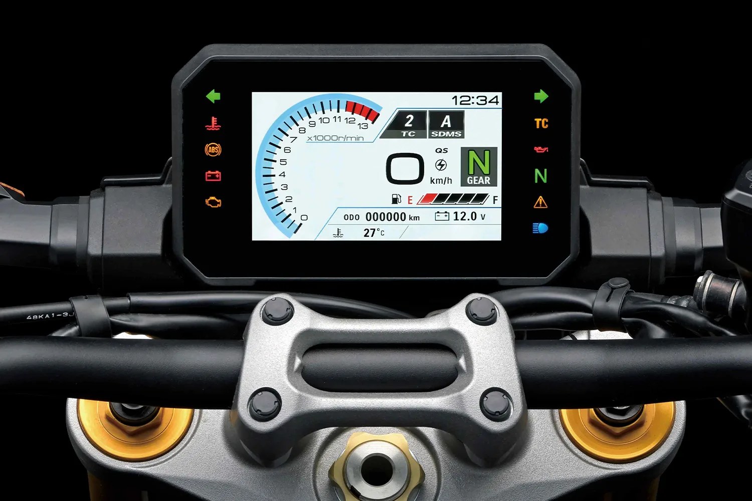 Digital motorcycle dashboard display showing tachometer, gear indicator (neutral), speedometer at 0 km/h, fuel gauge, odometer at 0 km, battery voltage at 12.0V, temperature at 27&deg;C, and various warning lights including ABS, engine, oil, traction control, and high beam indicators. The display is mounted on the handlebar with visible handlebar clamps and cables.