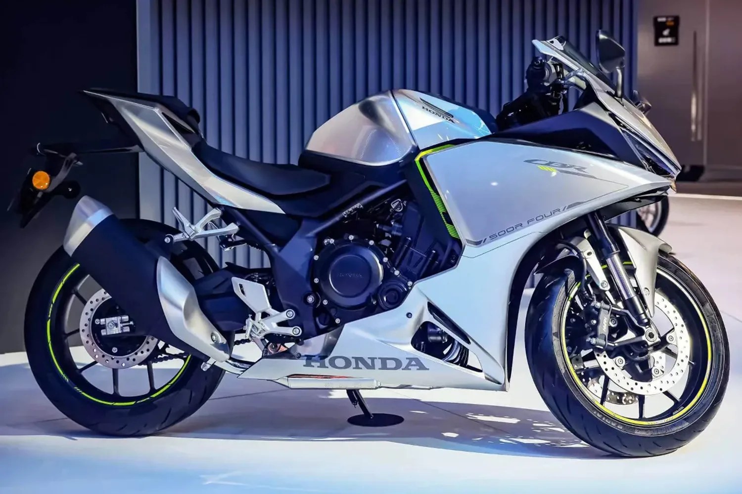Sporty silver and black Honda CBR 500R motorcycle with neon yellow accents on the wheels and fairings, featuring a sleek aerodynamic design and a comfortable seat.