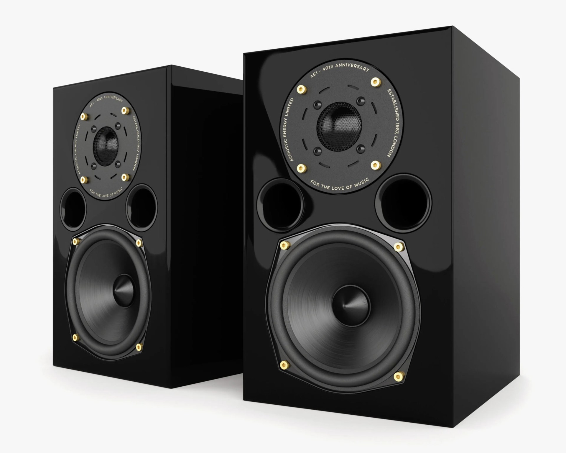 Pair of black bookshelf speakers with a glossy finish, featuring a large woofer at the bottom, two circular bass ports above it, and a tweeter at the top surrounded by gold screws. The tweeter plate has text that reads "AE1 - 40th ANNIVERSARY," "ACOUSTIC ENERGY LIMITED," "ESTABLISHED 1987 LONDON," and "FOR THE LOVE OF MUSIC.