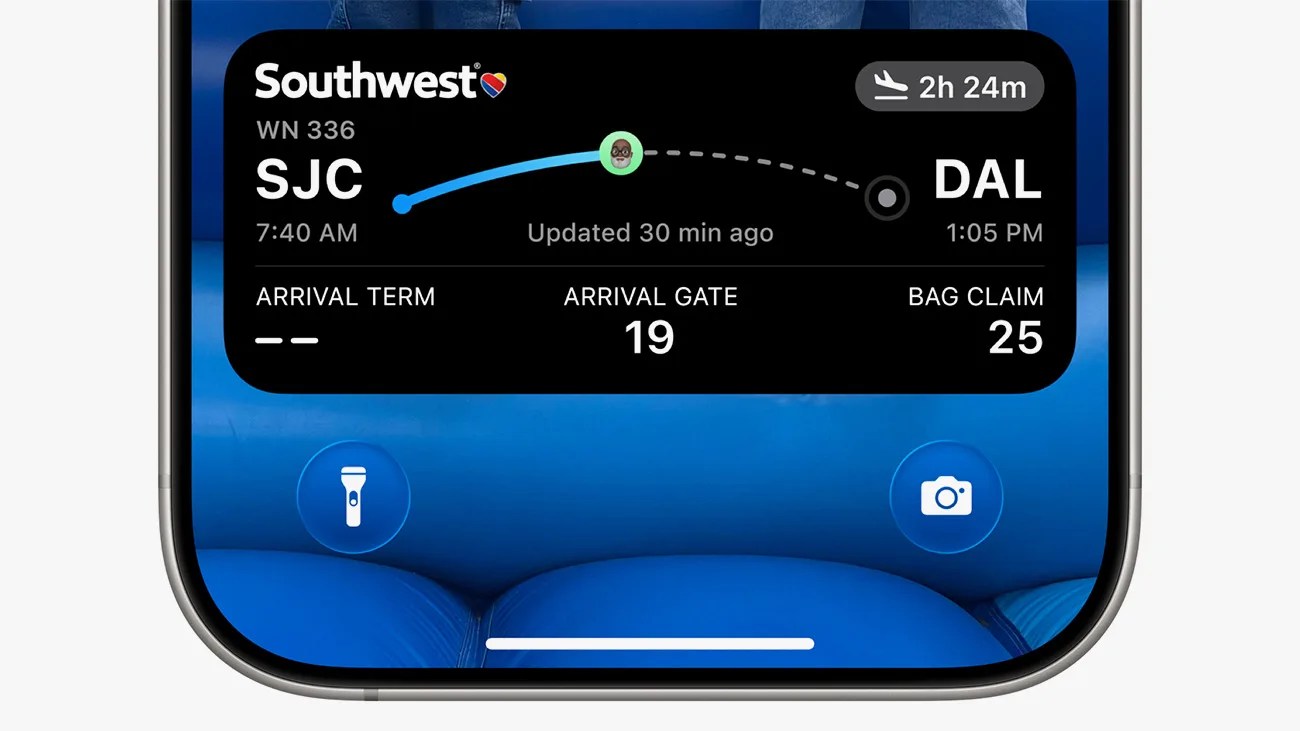 Flight information widget on a smartphone screen showing a Southwest Airlines flight WN 336 from SJC (San Jose) to DAL (Dallas) departing at 7:40 AM and arriving at 1:05 PM with a duration of 2 hours 24 minutes. The arrival gate is 19 and bag claim is 25. The widget also displays an updated time of 30 minutes ago. The phone screen background is blue with flashlight and camera icons at the bottom corners.