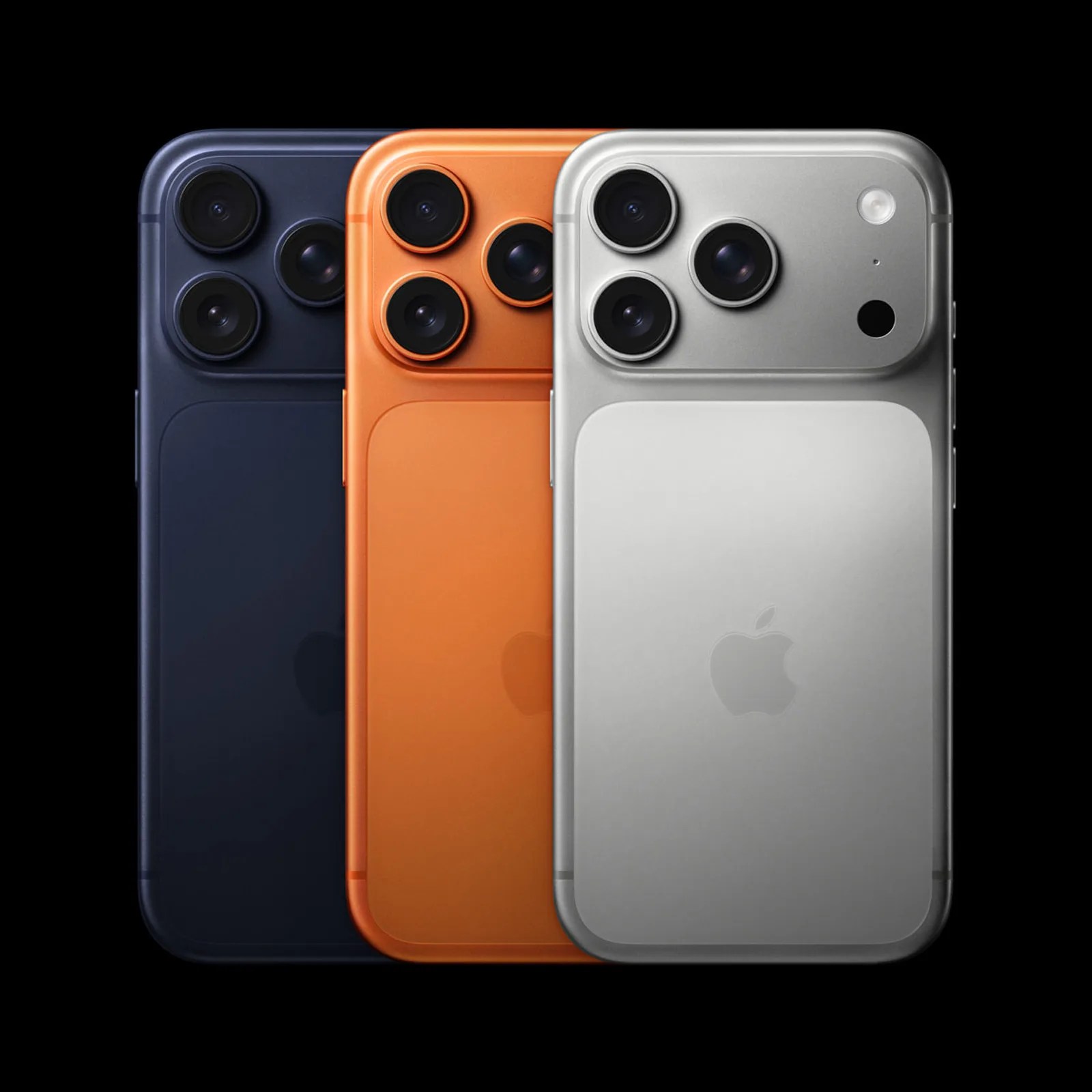 Three smartphones with triple camera setups are shown in a row. The phones are in different colors: dark blue on the left, orange in the middle, and silver on the right. Each phone has a large camera module housing three lenses and a flash, with the Apple logo visible on the back. The background is black, highlighting the phones.