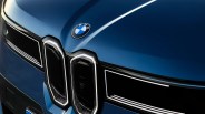 Close-up of the front grille and hood of a blue BMW car, featuring the BMW emblem above the distinctive kidney-shaped grille with chrome accents and black inserts.