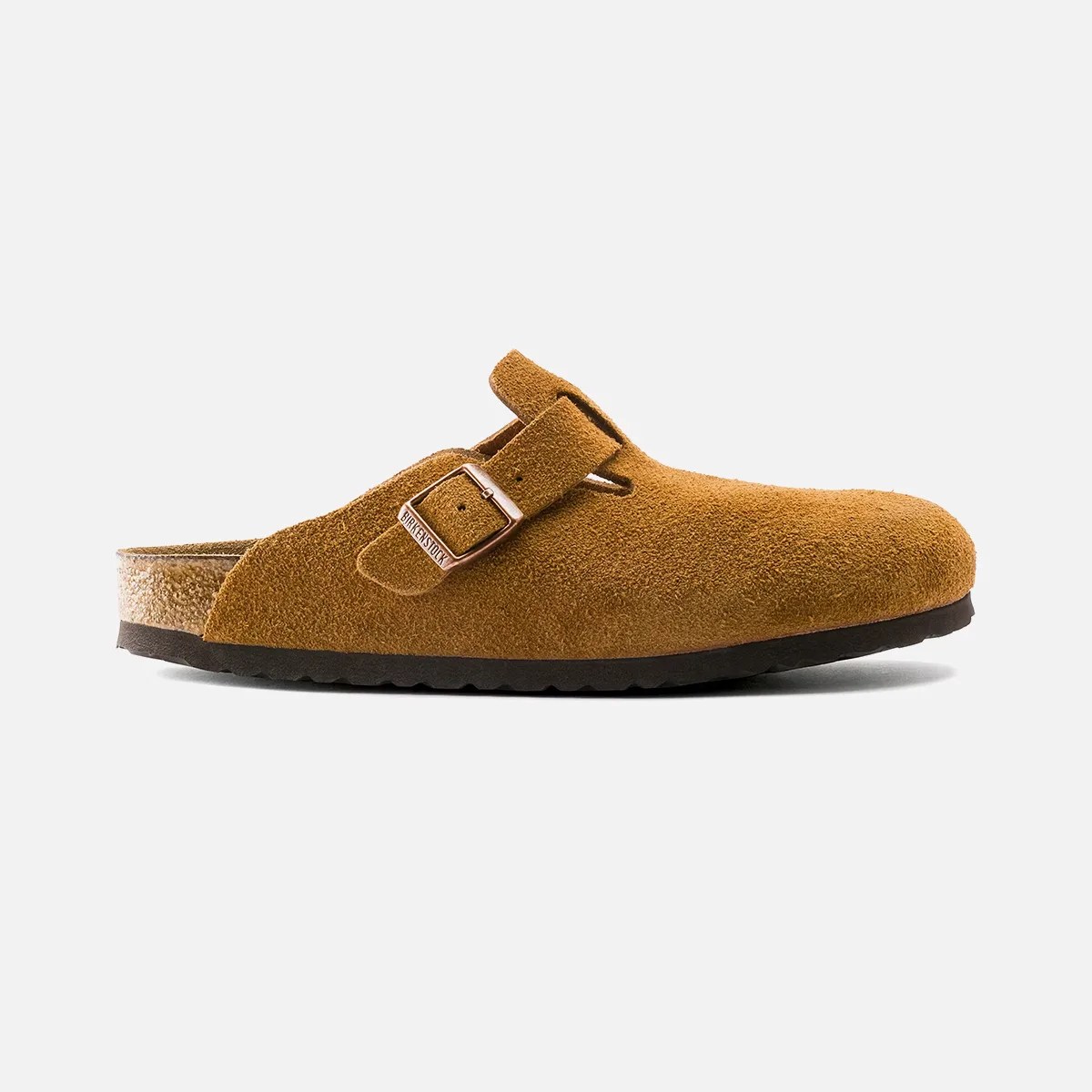 Brown suede slip-on clog with a rounded toe, featuring an adjustable strap with a metal buckle on the upper side. The sole is black with a textured grip, and the footbed appears to be cork-lined.