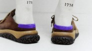 Brown shoes with thick, textured black soles and a cork-like midsole, featuring a bright purple suede heel collar. The shoes are worn with white socks that have the number "1774" printed near the top.