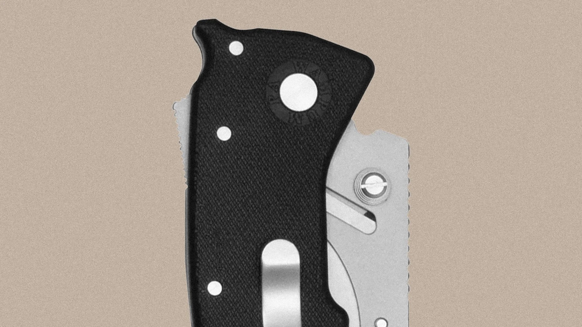Close-up of a folding knife handle with a textured black grip, three visible rivets, a circular pivot screw, and a partially visible silver metal blade with a thumb stud. The background is a plain beige color.