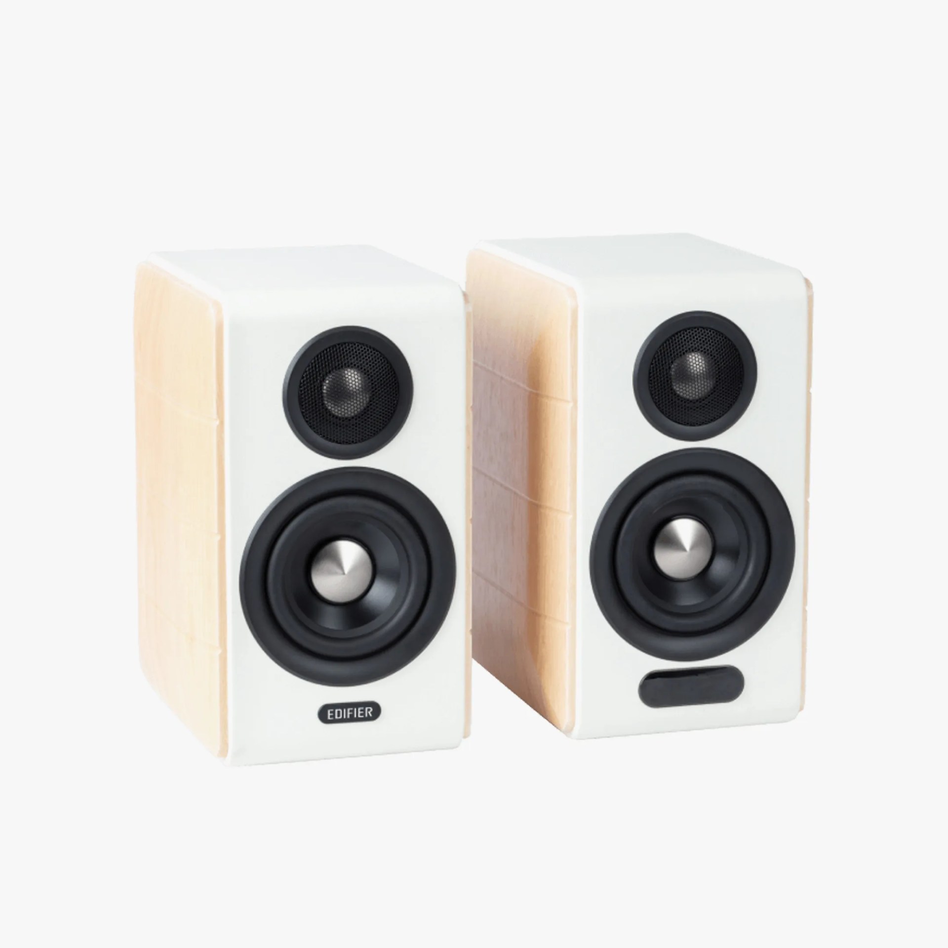 Two compact bookshelf speakers with white front panels and light wood side panels. Each speaker has a black tweeter at the top and a larger black woofer below it. The left speaker features the brand name