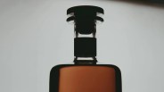 Close-up of the top portion of a glass bottle filled with amber liquid, featuring a black stopper and a black label around the neck.