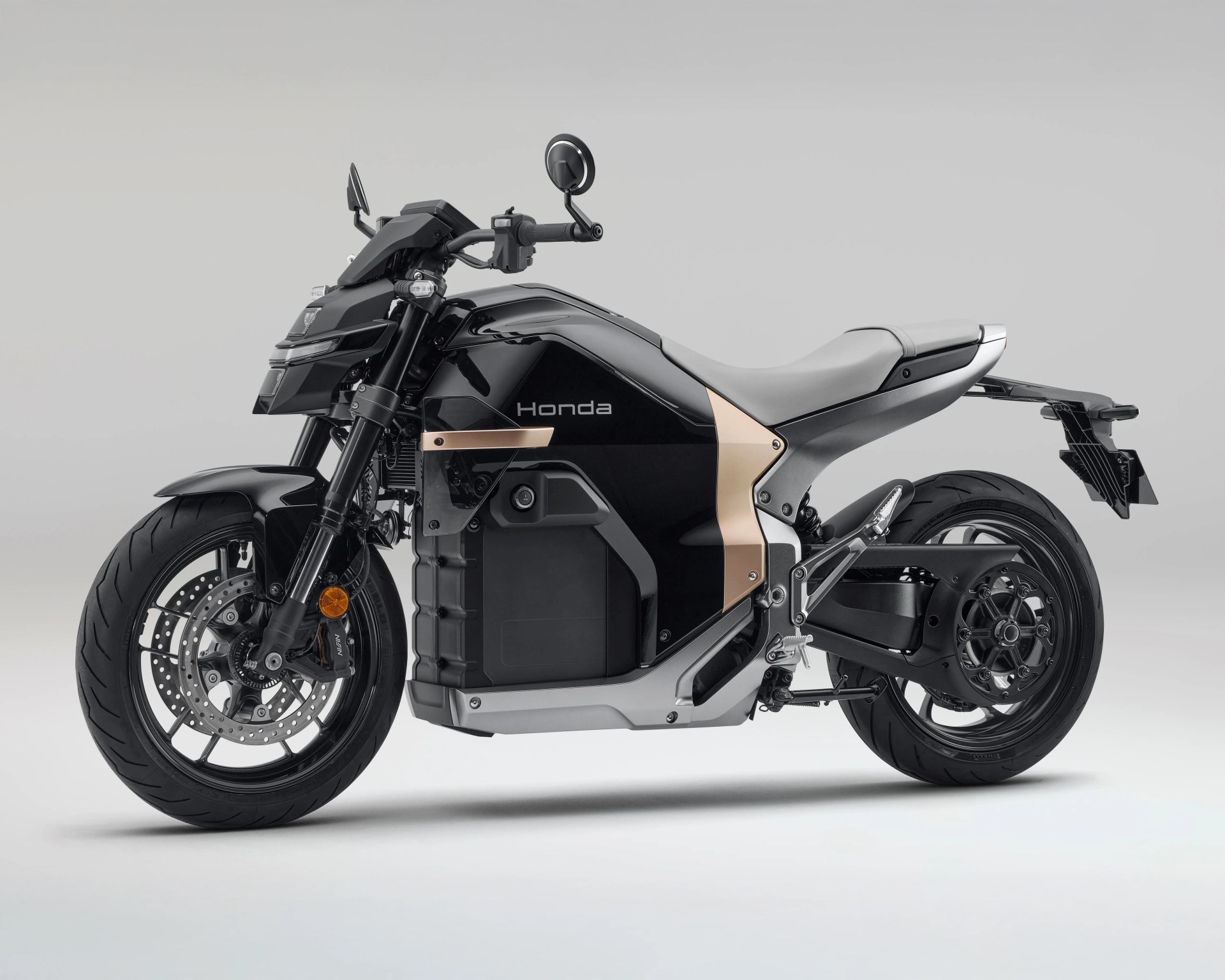Black and gray Honda electric motorcycle with a sleek, modern design, featuring a large battery compartment in the center, dual disc brakes on the front wheel, and a minimalist seat and rear fender.