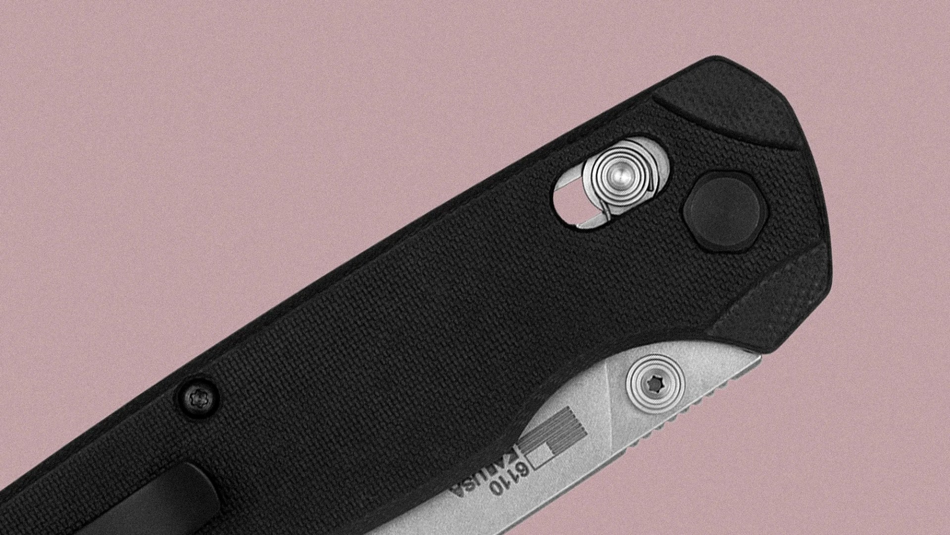 Close-up of a black folding knife handle with textured grip, showing a partially visible silver blade marked "610 USA" and metal screws near the pivot area.