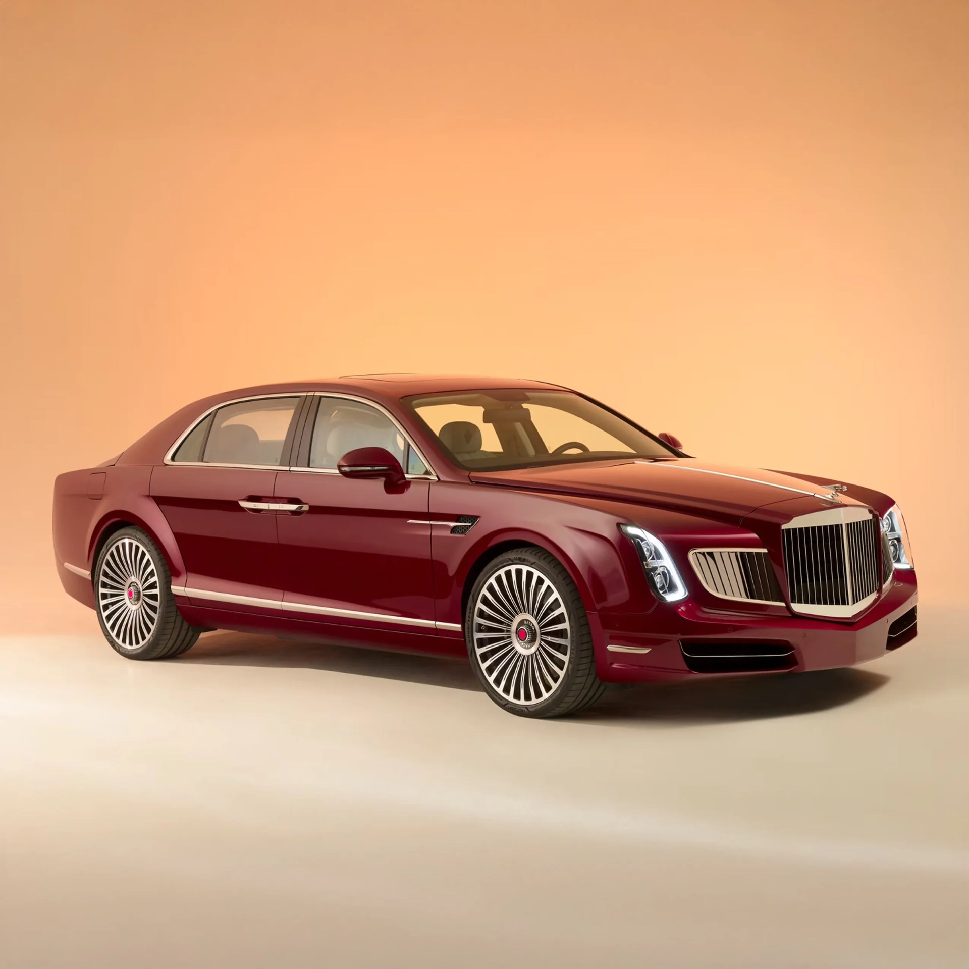 A luxurious, deep red sedan with a sleek, elongated body and large, intricate multi-spoke wheels. The car features a prominent, vertically slatted chrome grille, distinctive LED headlights, and chrome accents along the sides and door handles. The background is a smooth gradient of warm beige to light orange.