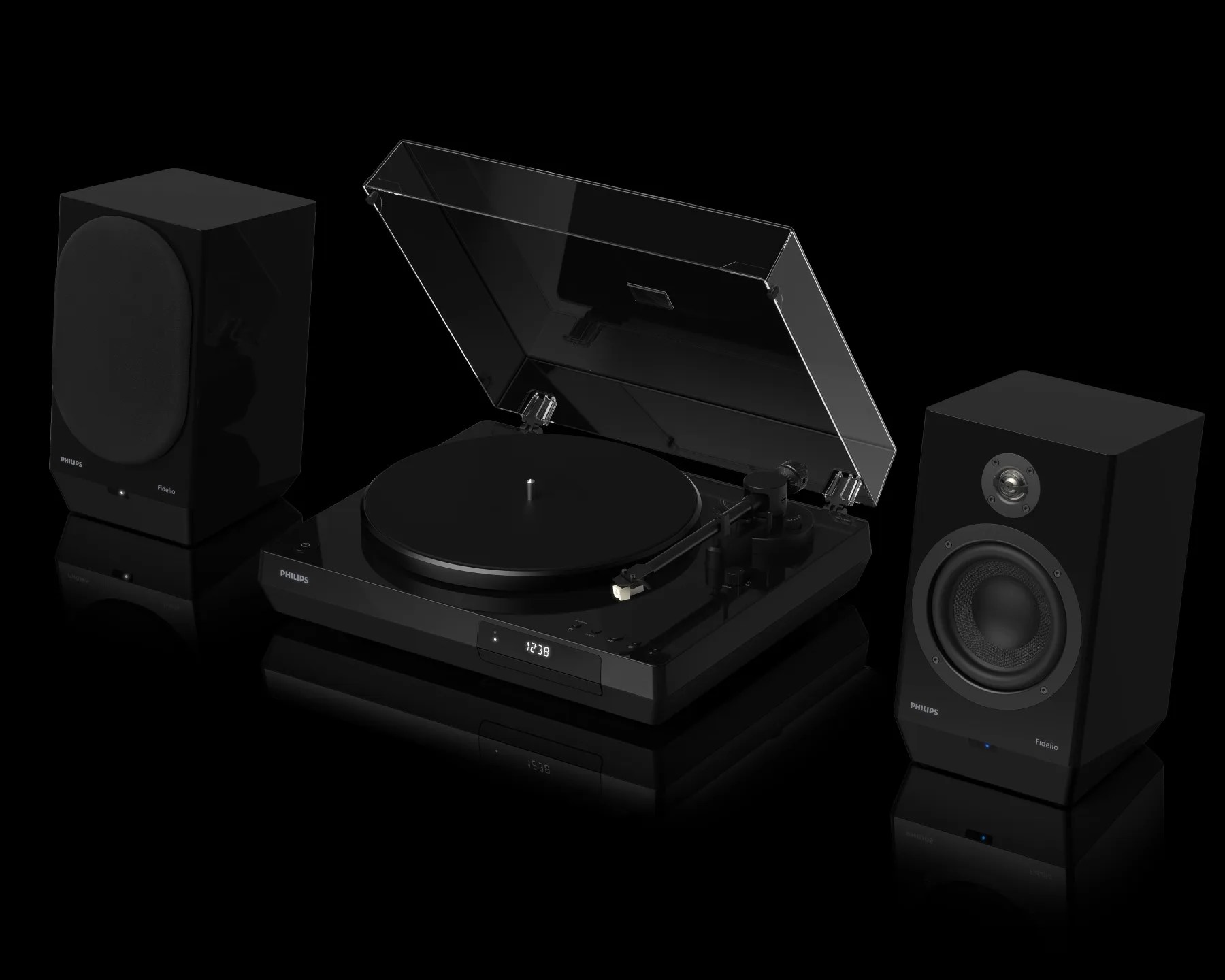 Black Philips Fidelio turntable with a transparent dust cover open, flanked by two black Fidelio speakers, one with a fabric cover and the other showing the speaker drivers. The turntable has a digital clock display on the front.