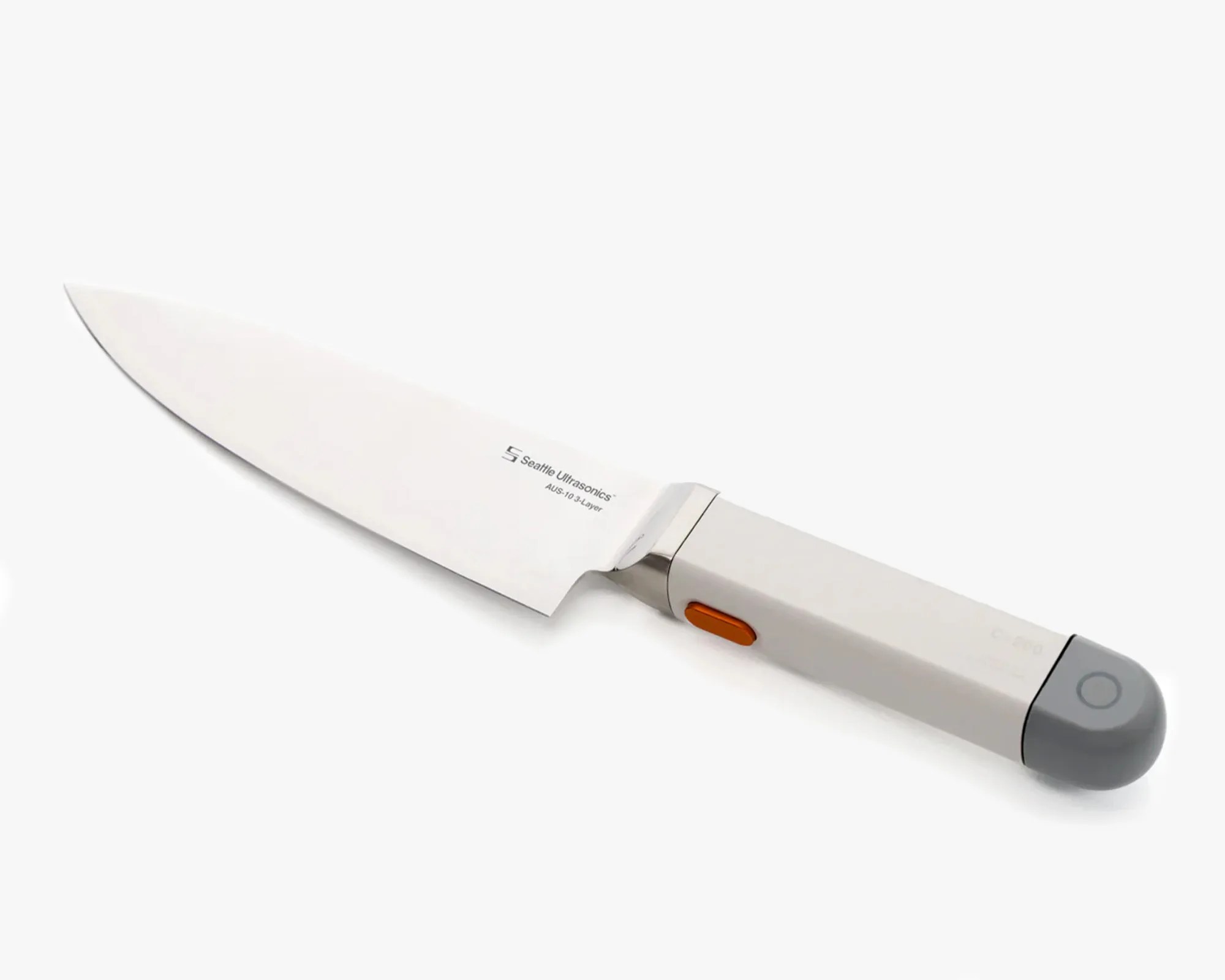 A sleek kitchen knife with a stainless steel blade labeled "Seattle Ultrasonics AUS-10 3-Layer." The handle is modern and rectangular, primarily white with a gray rounded end featuring a circular button, and an orange button on the side. The design suggests it may have electronic or smart features.