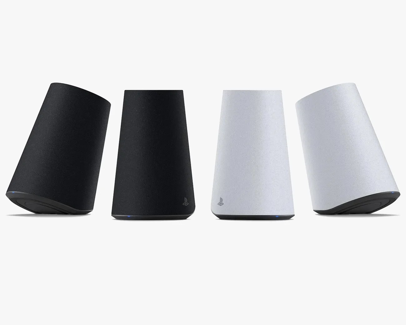 Four PlayStation 5 Pulse 3D wireless speakers are shown, two in black and two in white. Each speaker has a sleek, trapezoidal shape with a fabric covering and a small PlayStation logo near the bottom. The speakers are positioned upright and slightly tilted on a white background.