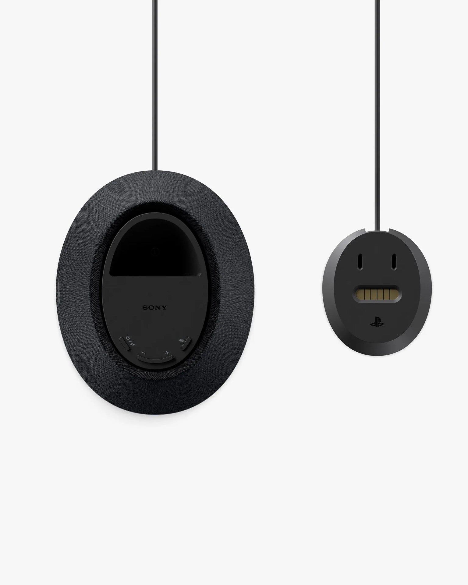 Two black oval-shaped electronic devices are shown from the back, each hanging by a cable. The larger device on the left has a fabric-covered outer ring and a central panel with the Sony logo and several buttons, including volume controls and a microphone mute button. The smaller device on the right has a simpler design with two vertical slots and a horizontal slot resembling a face, and a PlayStation logo below the slots. Both devices have a sleek, modern appearance.