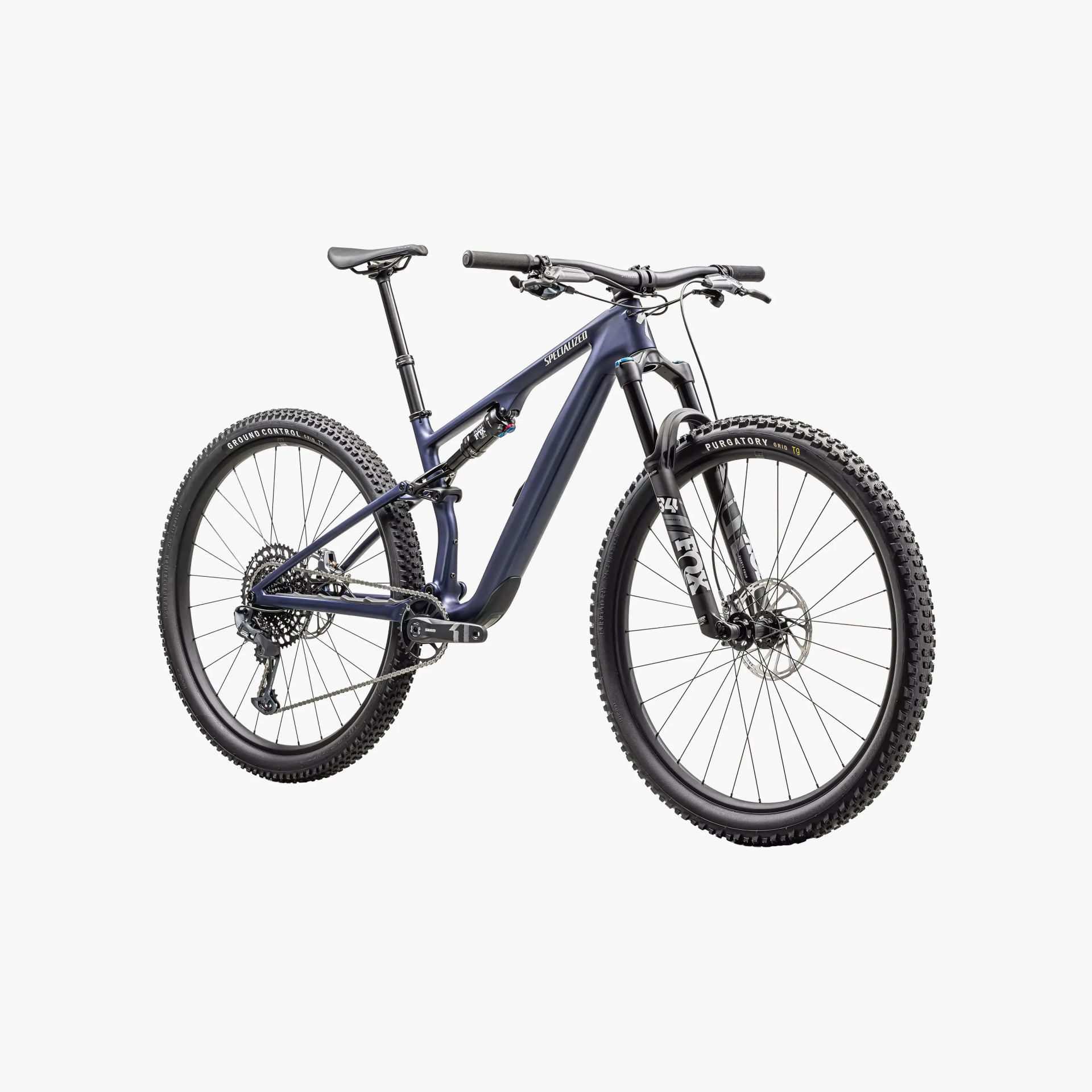 Mountain bike with a matte dark blue frame, full suspension, and black components including handlebars, seat, and tires. The front fork is branded FOX with "34" visible, and the tires have knobby treads for off-road use. The bike features disc brakes and a Shimano drivetrain.